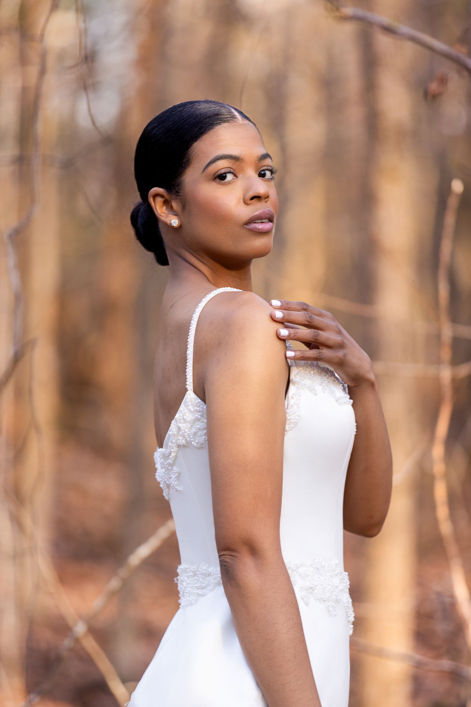 Elegant white dress with lace details captured in a wooded setting during golden hour.