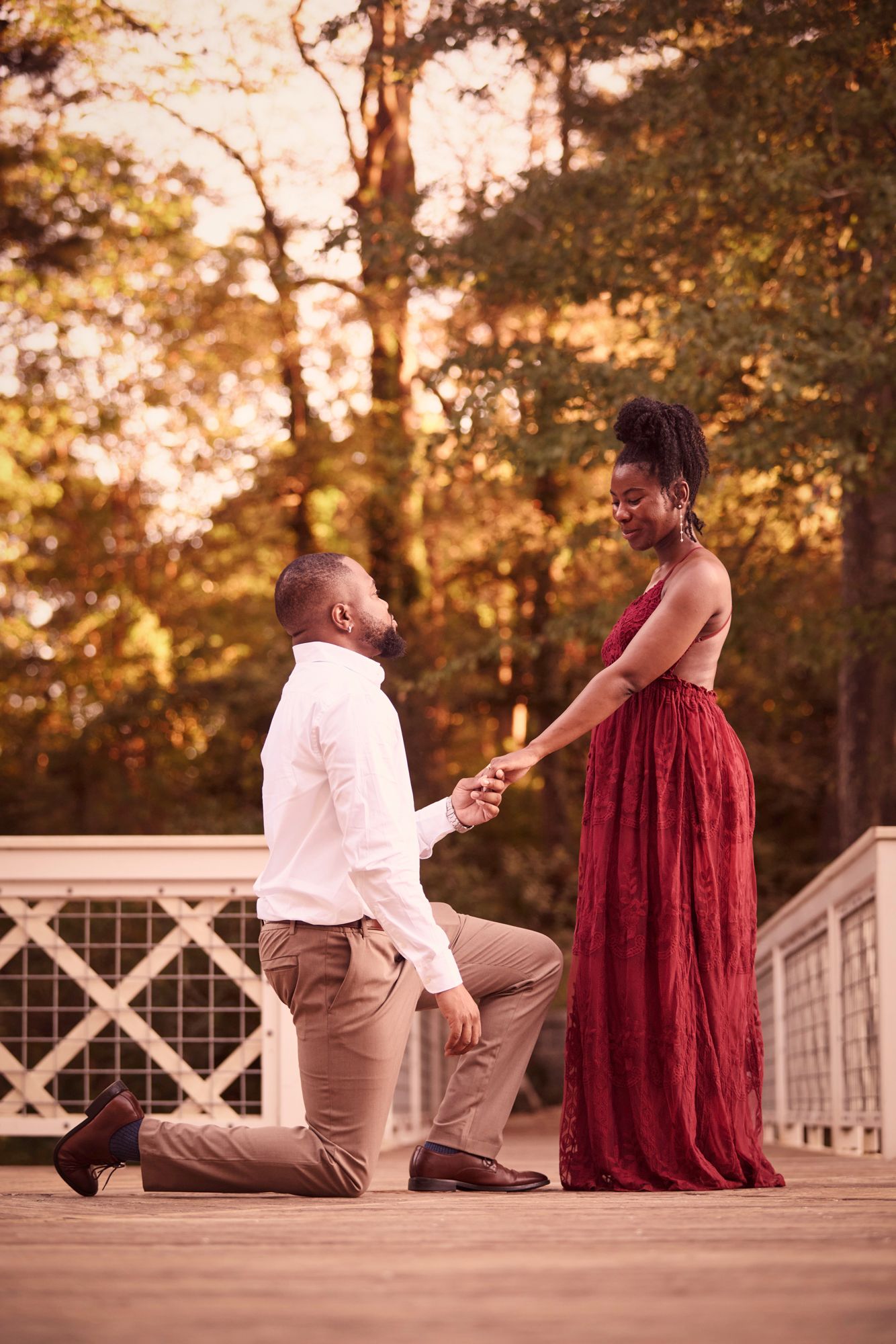 A romantic proposal scene on a wooden deck during golden hour.