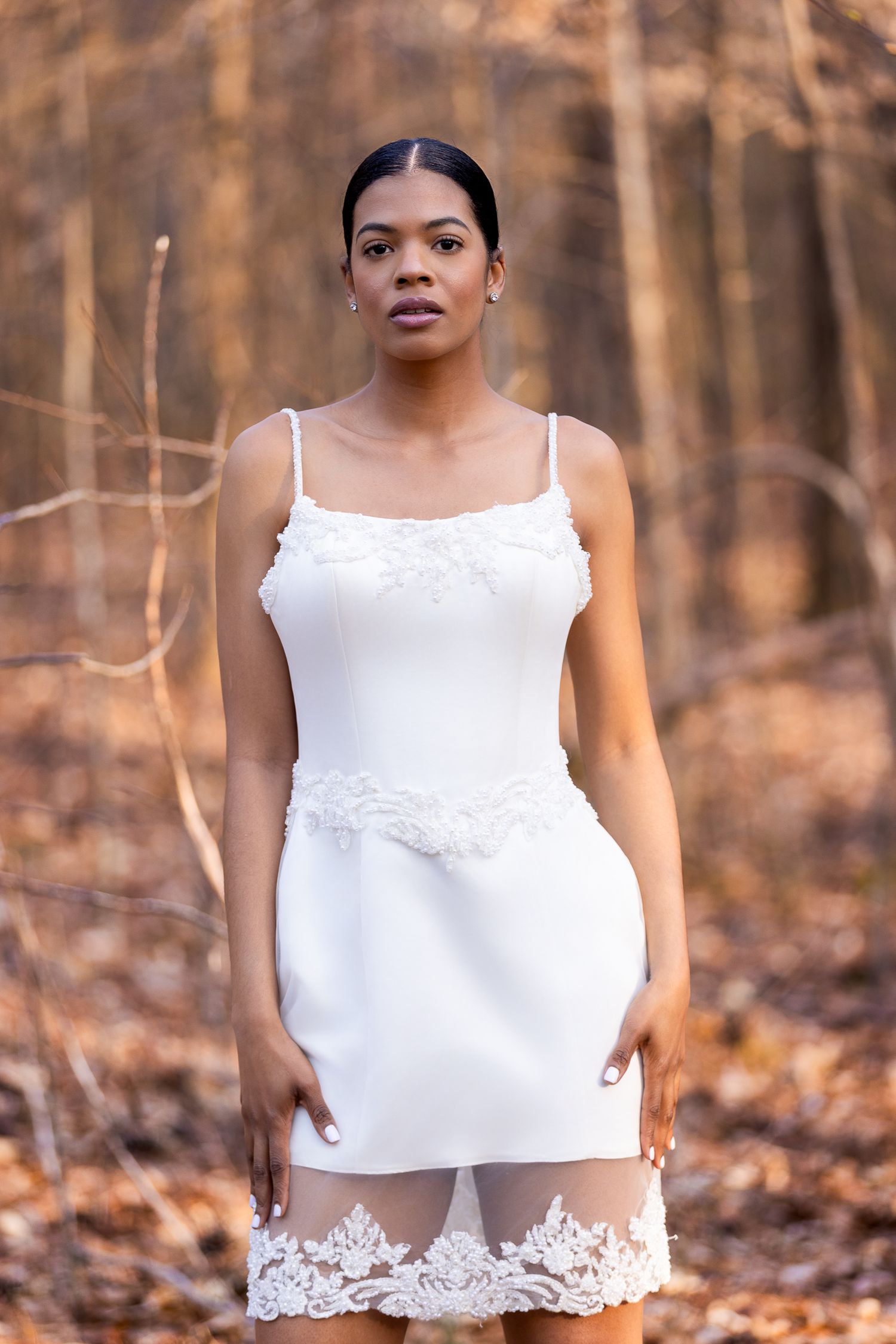 A white lace-trimmed crop top photographed in a fall forest setting with warm autumn colors.
