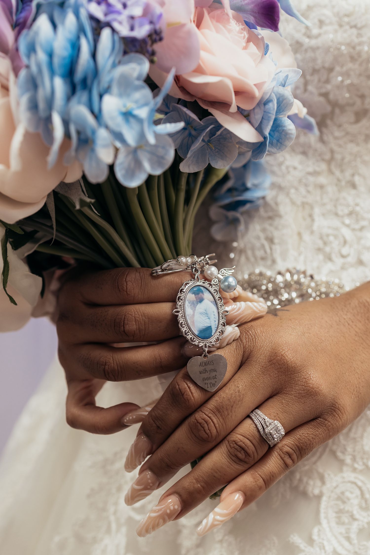 Bridal hands holding pastel bouquet with ornate vintage jewelry and manicured nails.