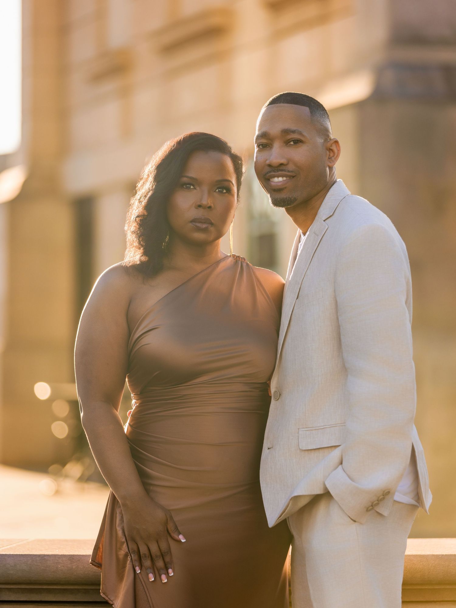 Couple in brown and white outfits posing during golden hour photography session.