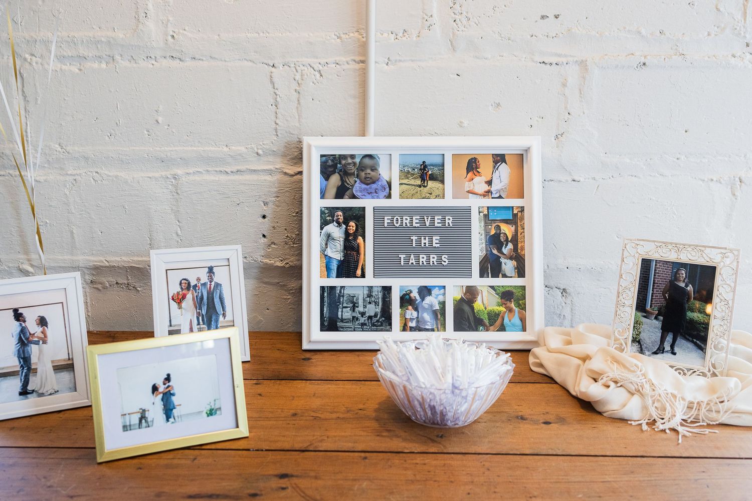 White photo frames displayed on a wooden surface against a textured white wall.