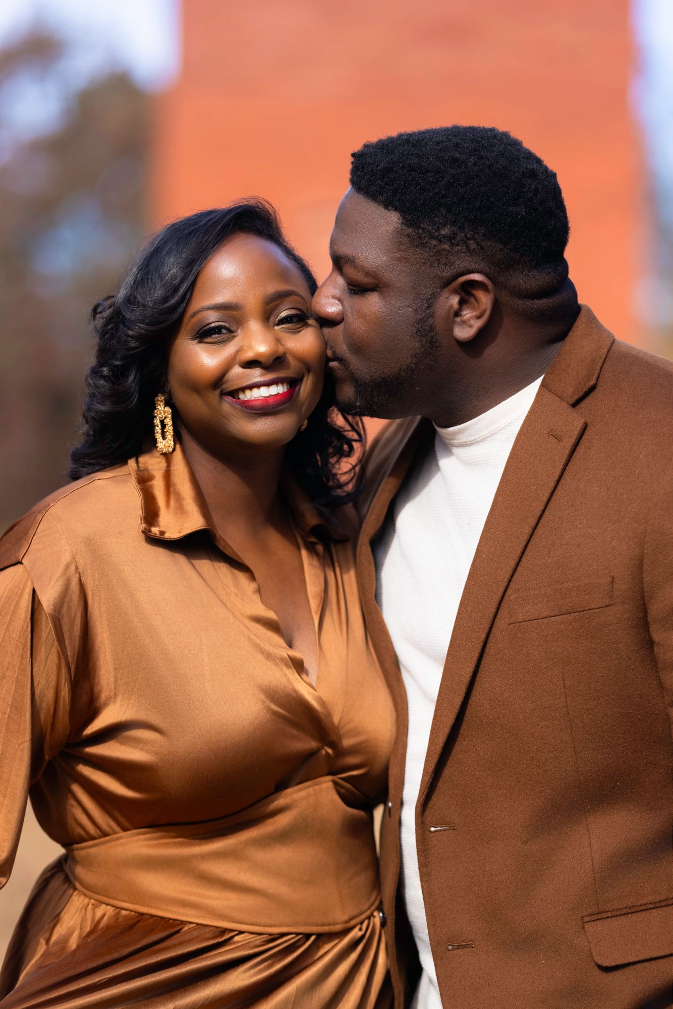 Couple in brown and white outfits share romantic moments during outdoor photoshoot.