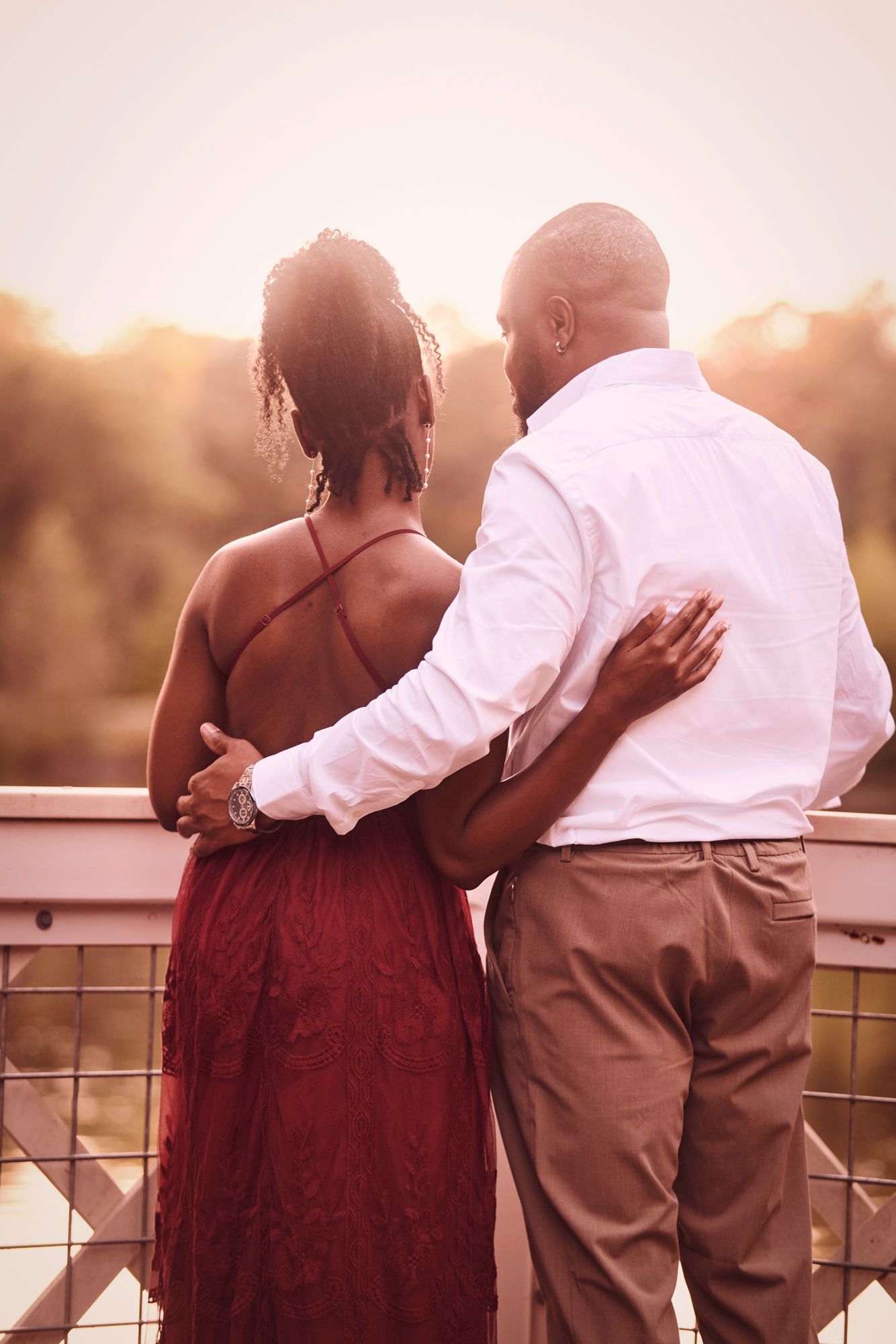 Couple sharing a romantic moment while leaning on a railing at sunset.