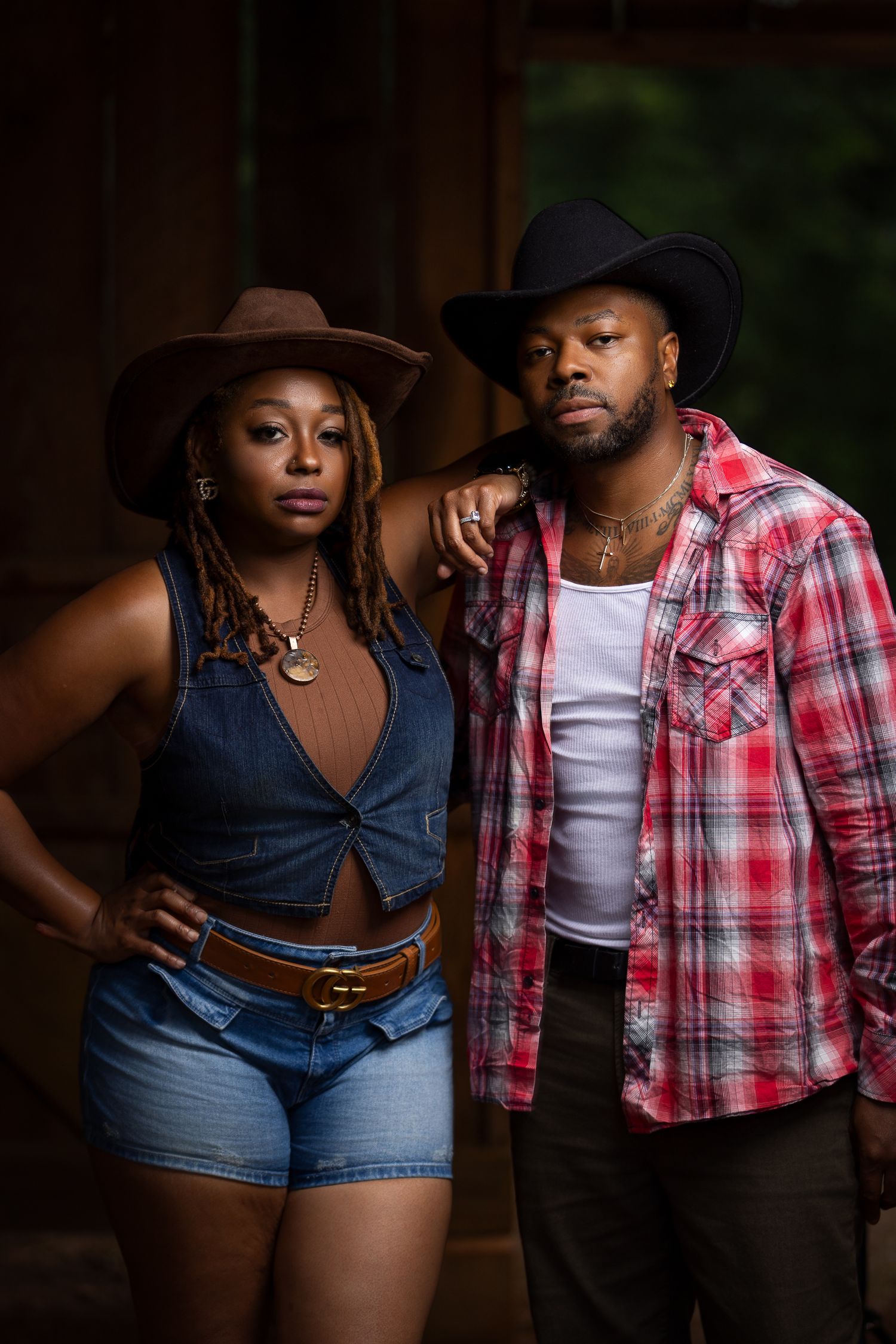 Atmospheric portrait of people in country western attire posing in a dimly lit barn.