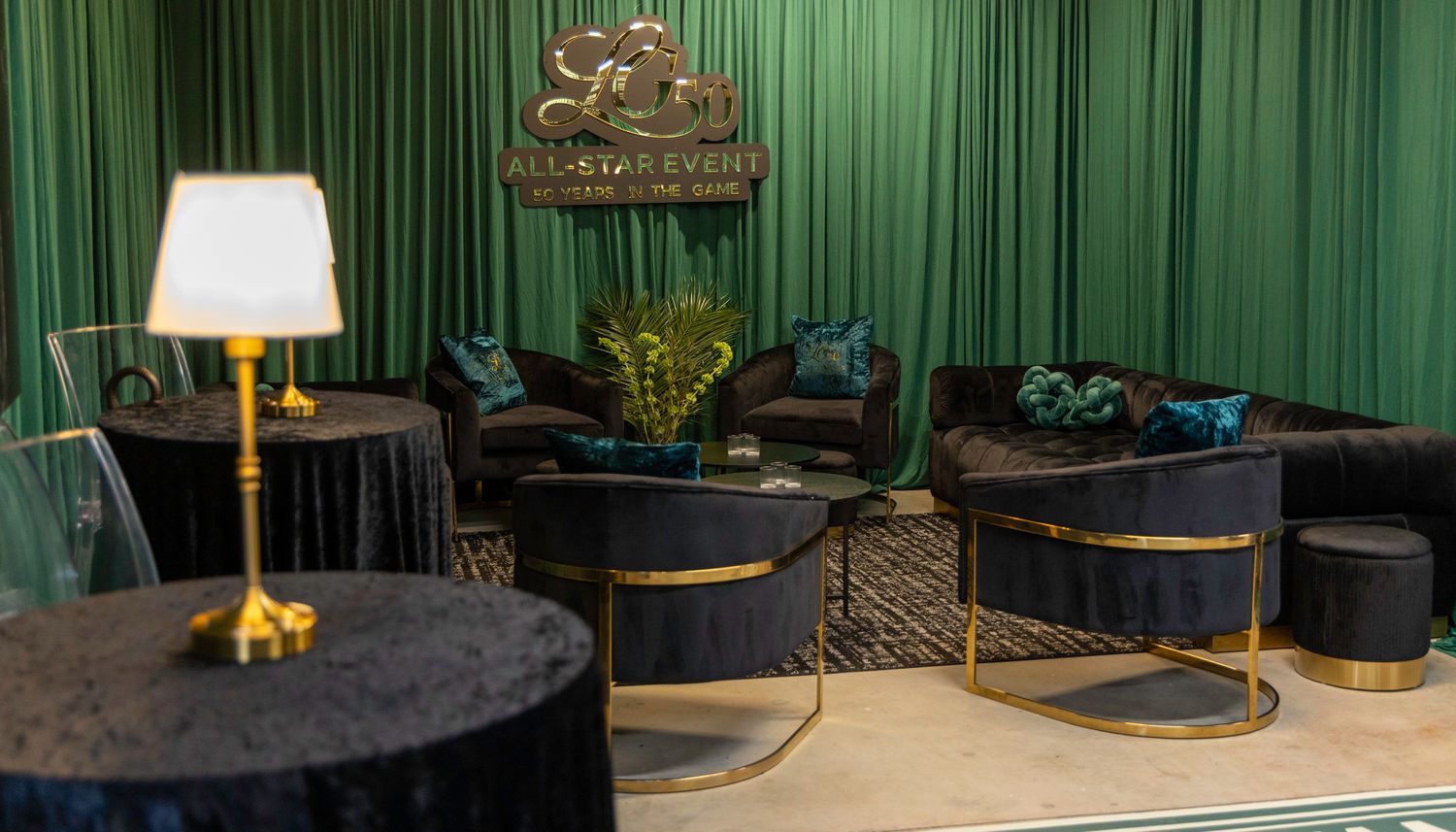 Modern event venue with emerald green drapes and elegant furniture setup.
