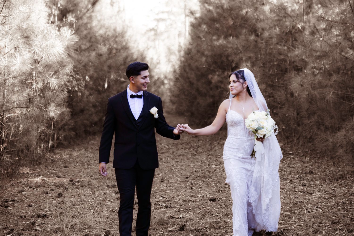 Wedding couple in formal attire creates fun poses against a natural outdoor backdrop.