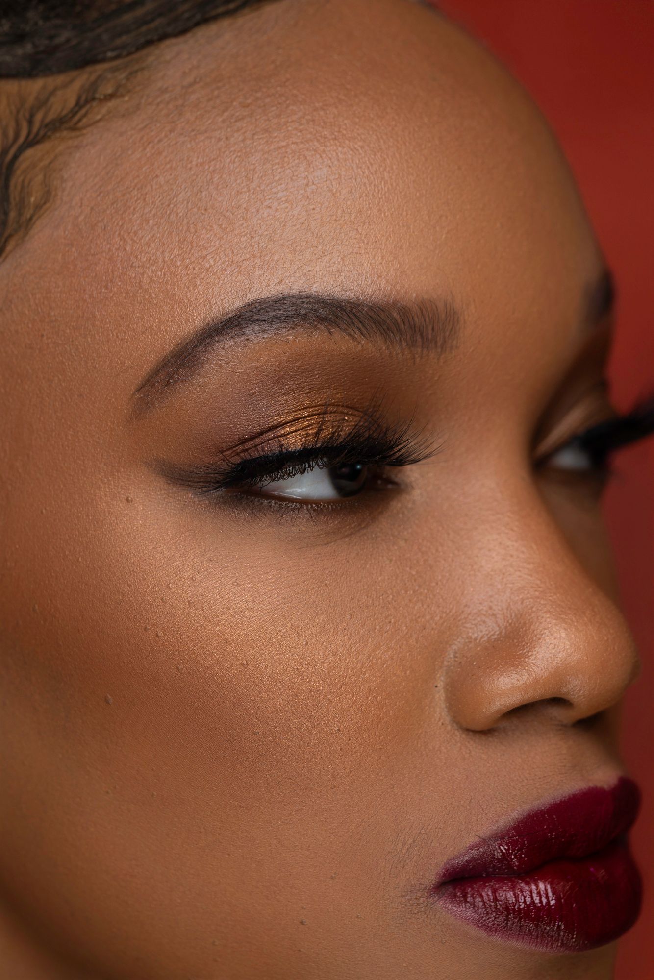 Close-up beauty shot showcasing dramatic burgundy lipstick and smokey eye makeup.