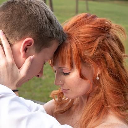 Intimate close-up of a redhead bride and groom sharing a tender moment outdoors.