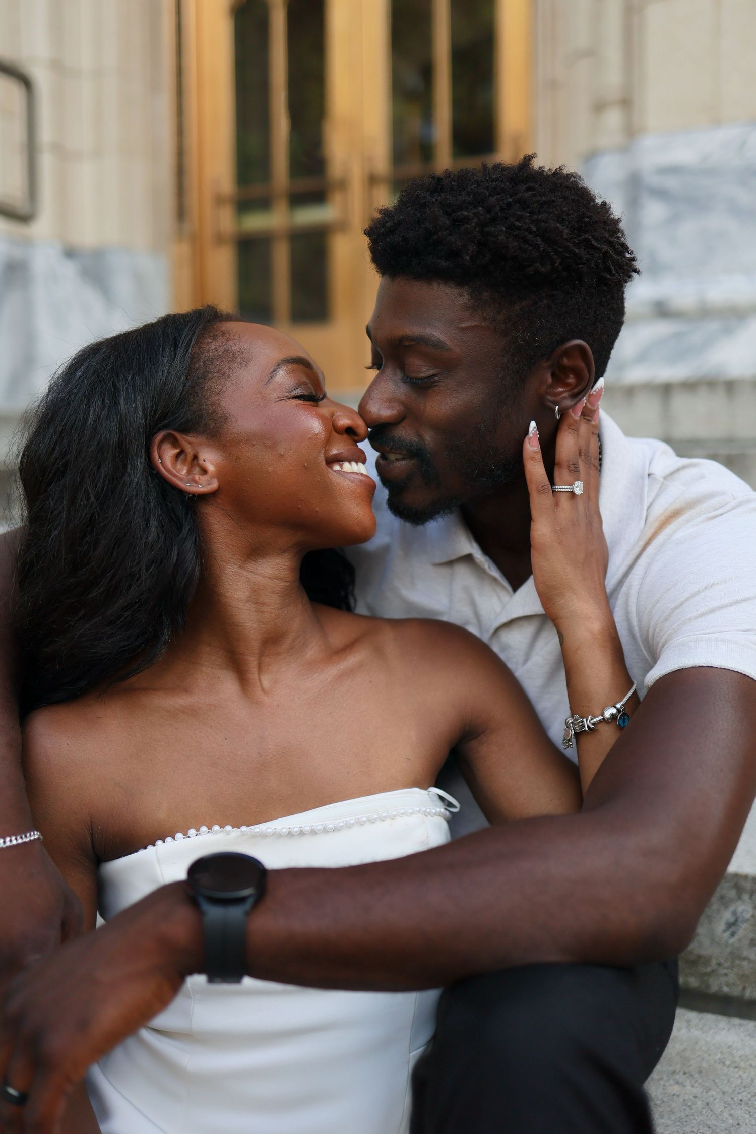 A joyful Black couple shares a romantic moment, nearly kissing, as the bride smiles in a white strapless dress.