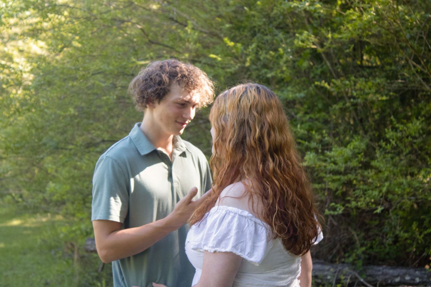 Young couple sharing an intimate conversation outdoors in a lush green park setting.
