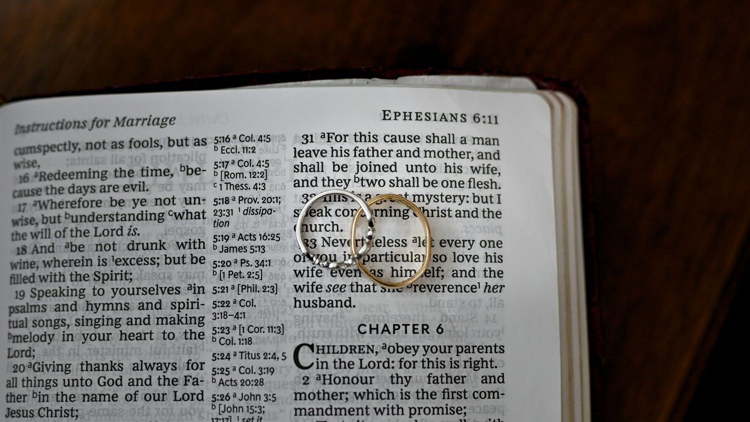 Open Bible displaying Ephesians 6:11 with wedding rings resting on the marriage passage.