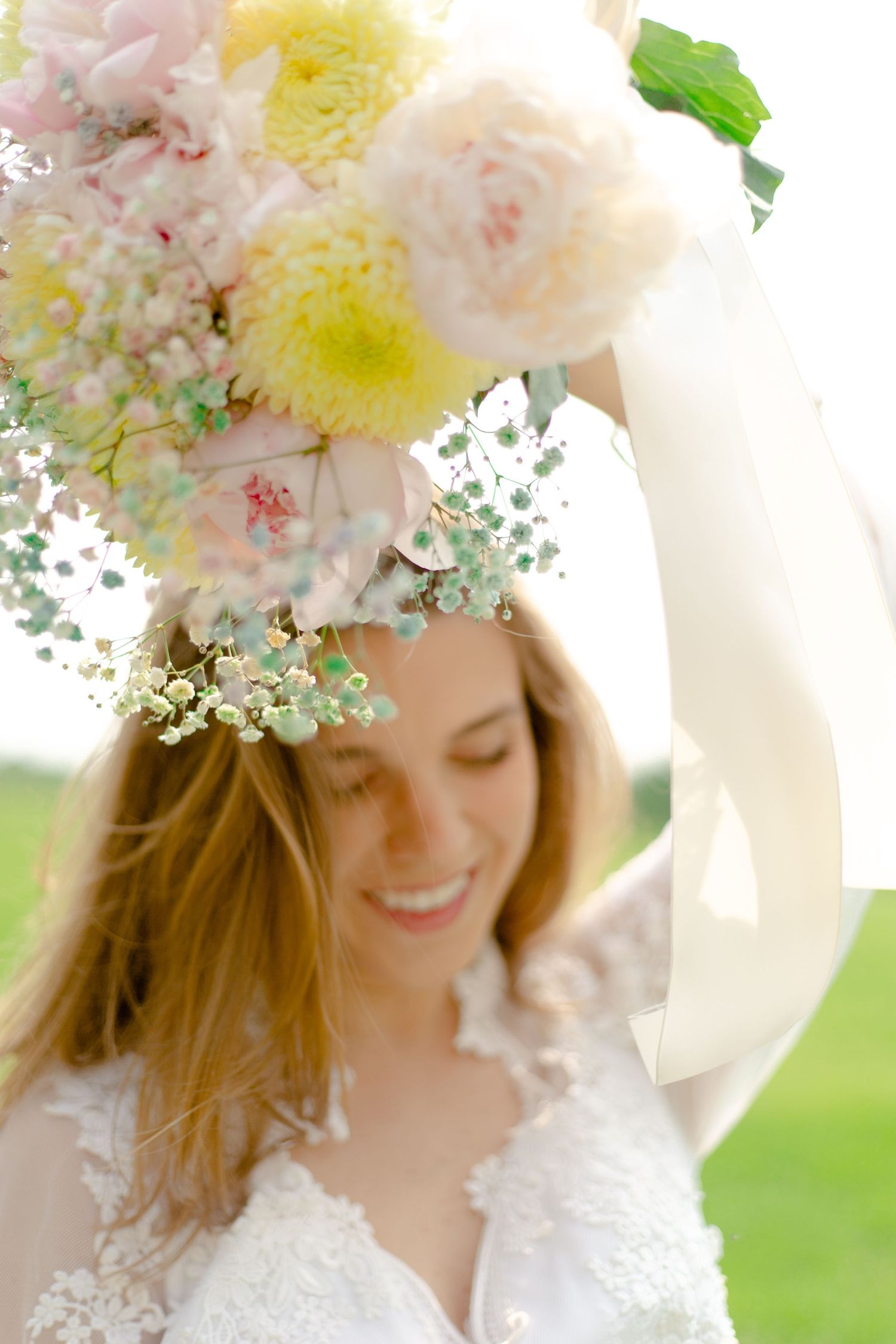 Bride laughing in a field with her bouquet.