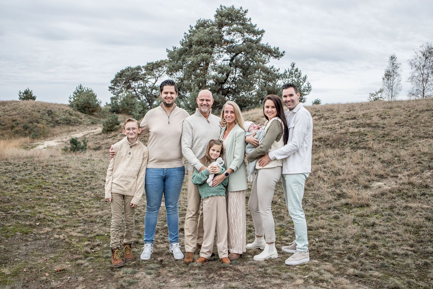 Extended family of eight adults and children posing together on open heathland.