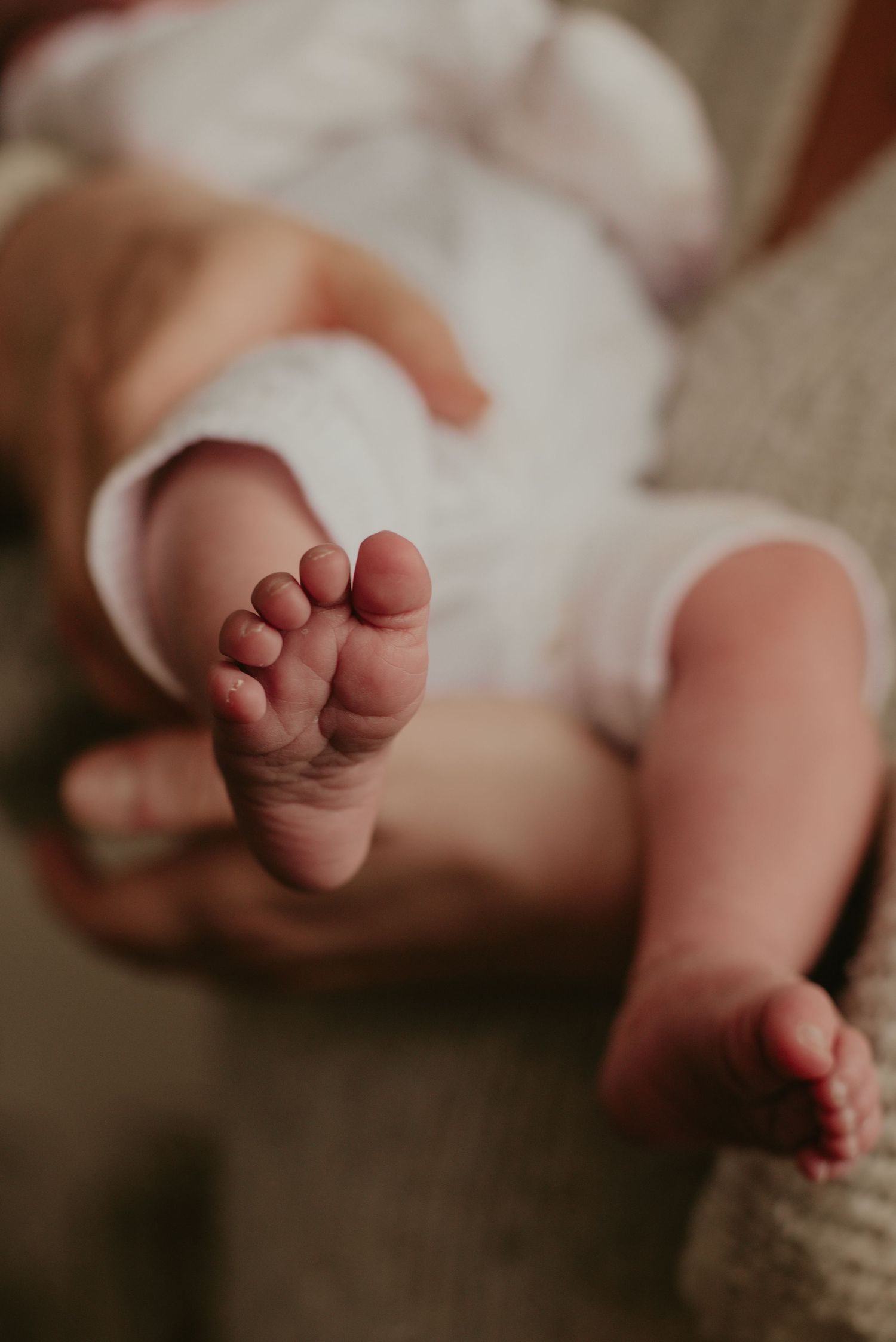Close-up of tiny baby feet against a neutral textured background.