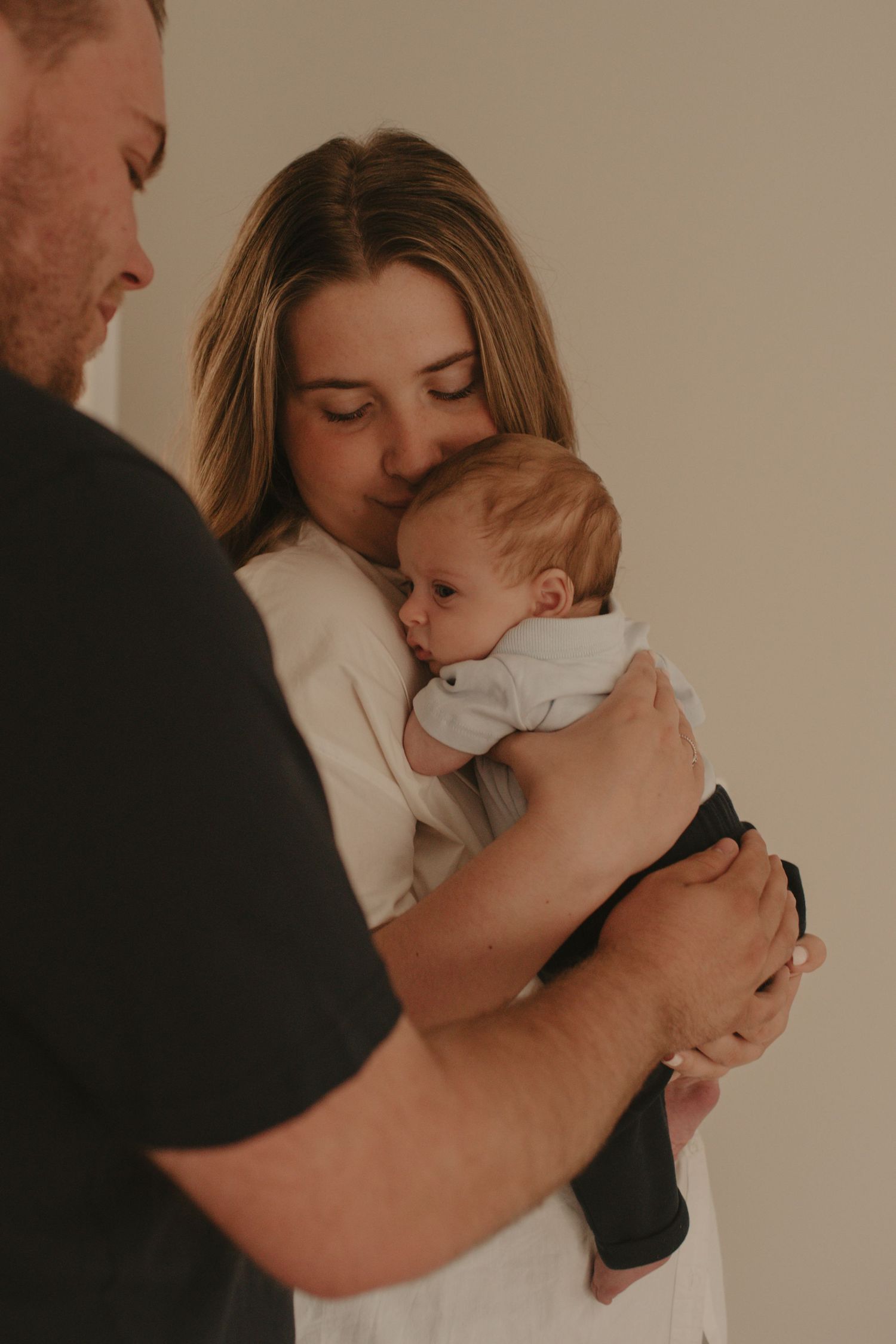 Intimate family portrait session with soft lighting against neutral background.