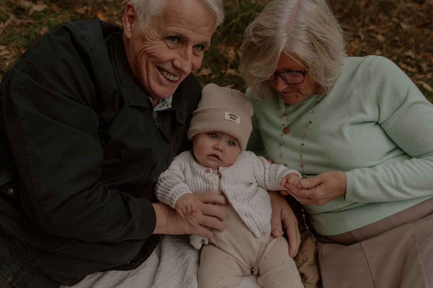 Family members sharing tender moments together outdoors during an autumn photoshoot in warm clothing.