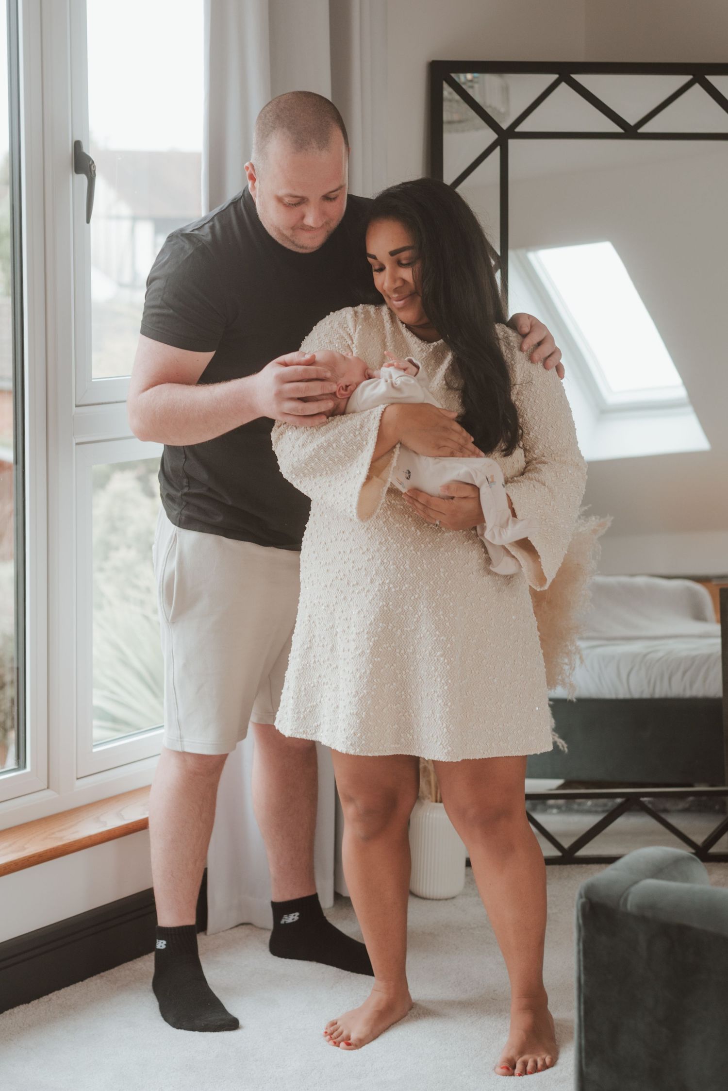 Family lifestyle moment showing bare feet and white dress against dark couch.