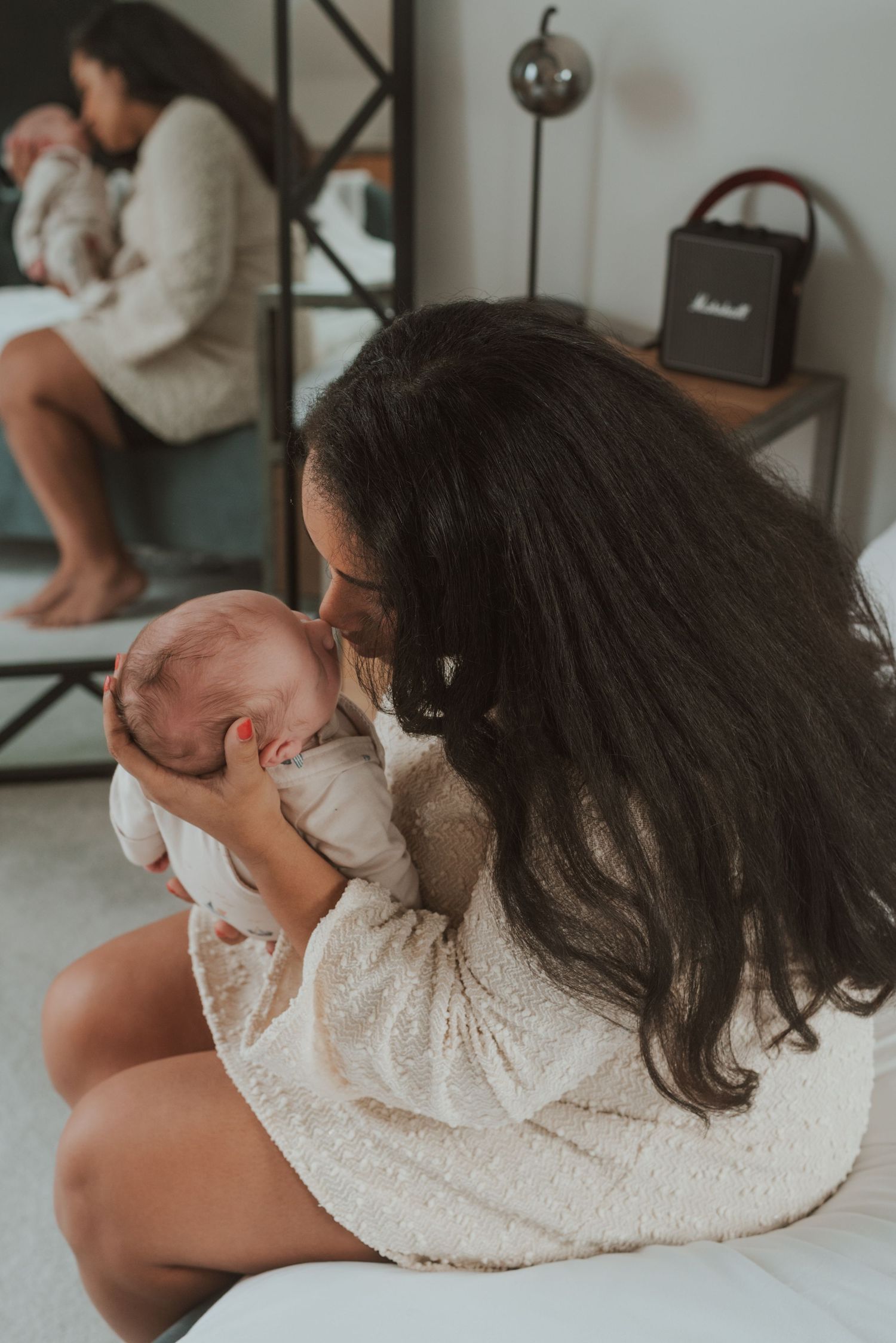 An intimate moment captured as a baby is cradled in a cozy white sweater dress.