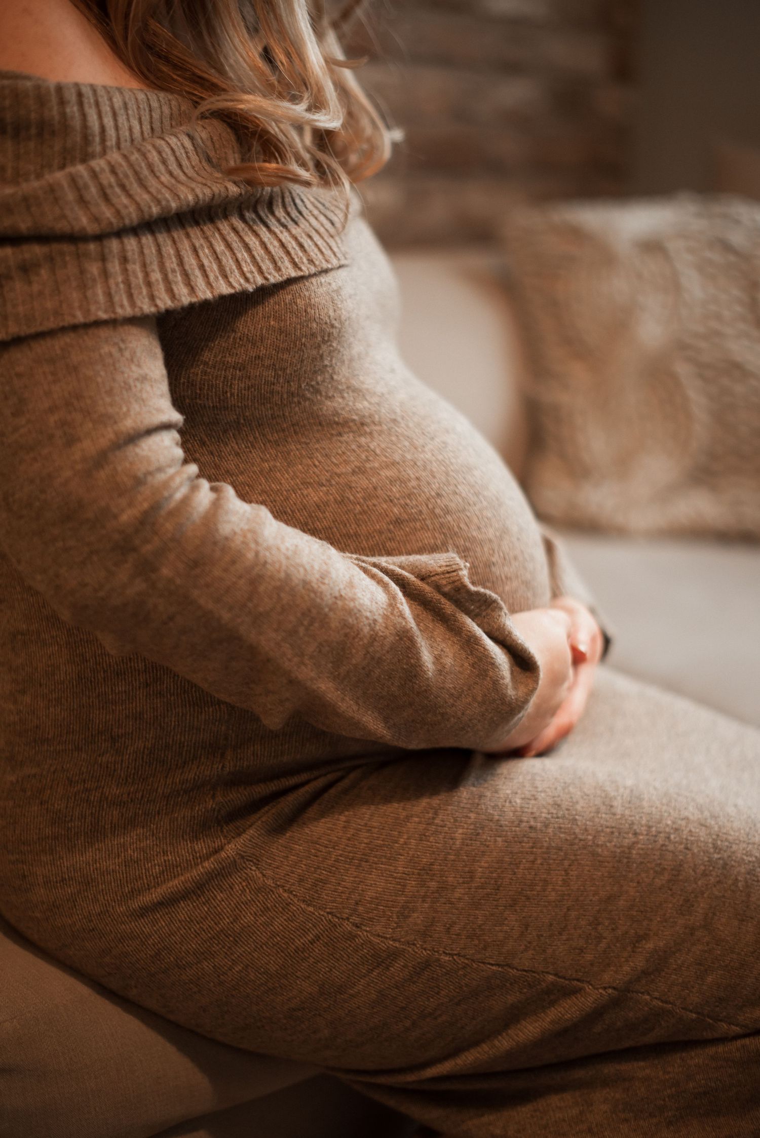 Person wearing a warm brown sweater sitting comfortably in soft natural lighting.