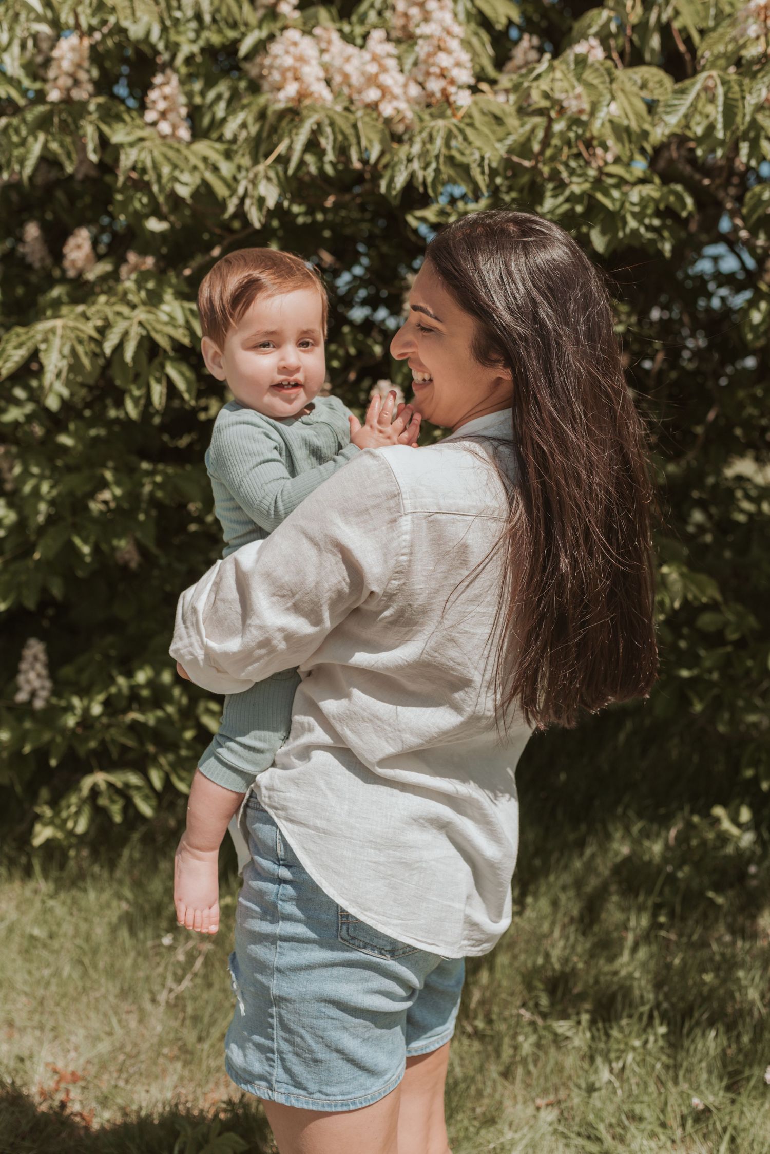 Playful moment captured outdoors with blooming trees in the background on a sunny day.