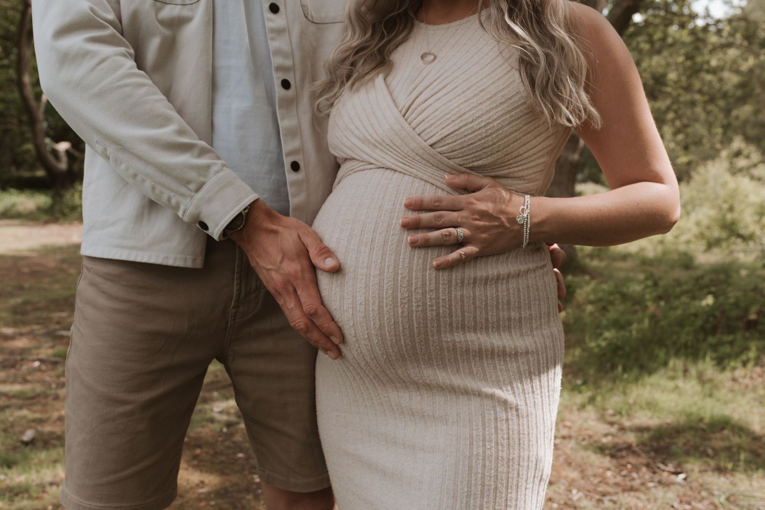 An intimate outdoor maternity session with a couple wearing white and neutral tones.