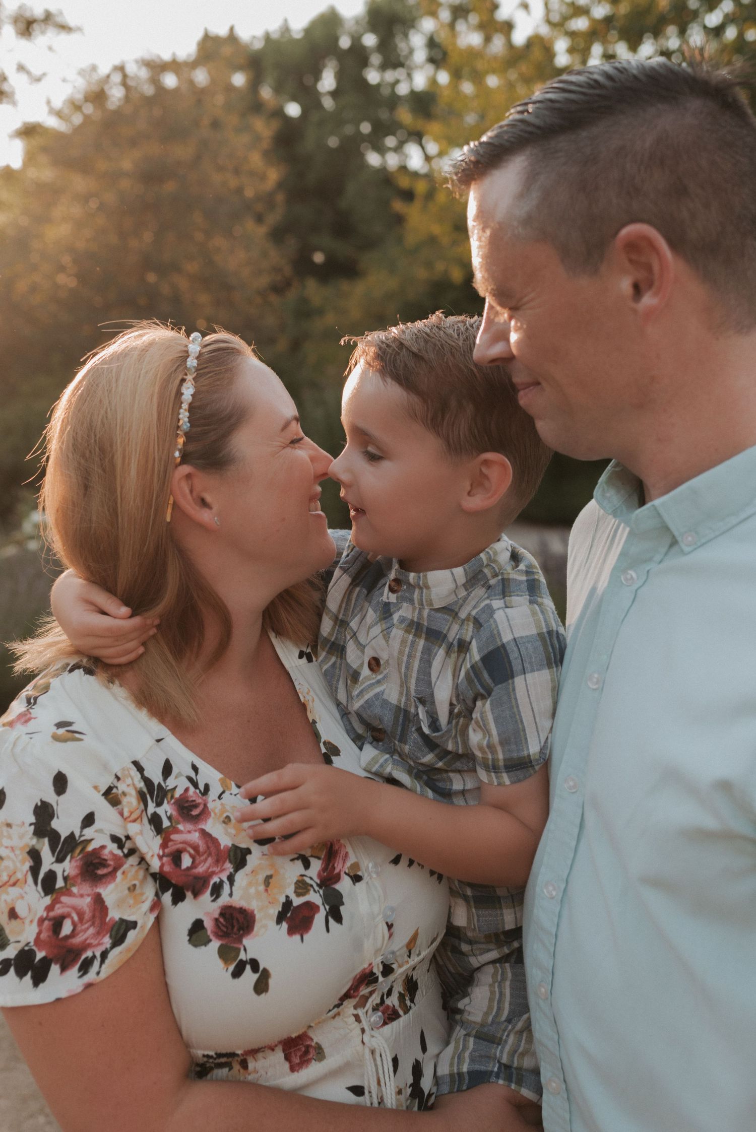 A family of three shares intimate moments in a series of tender outdoor poses against an autumn backdrop.