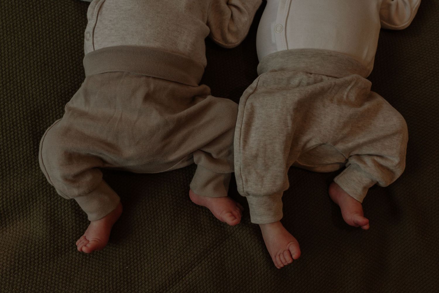 Baby feet in white socks against a dark background showing a progression of movement and steps.