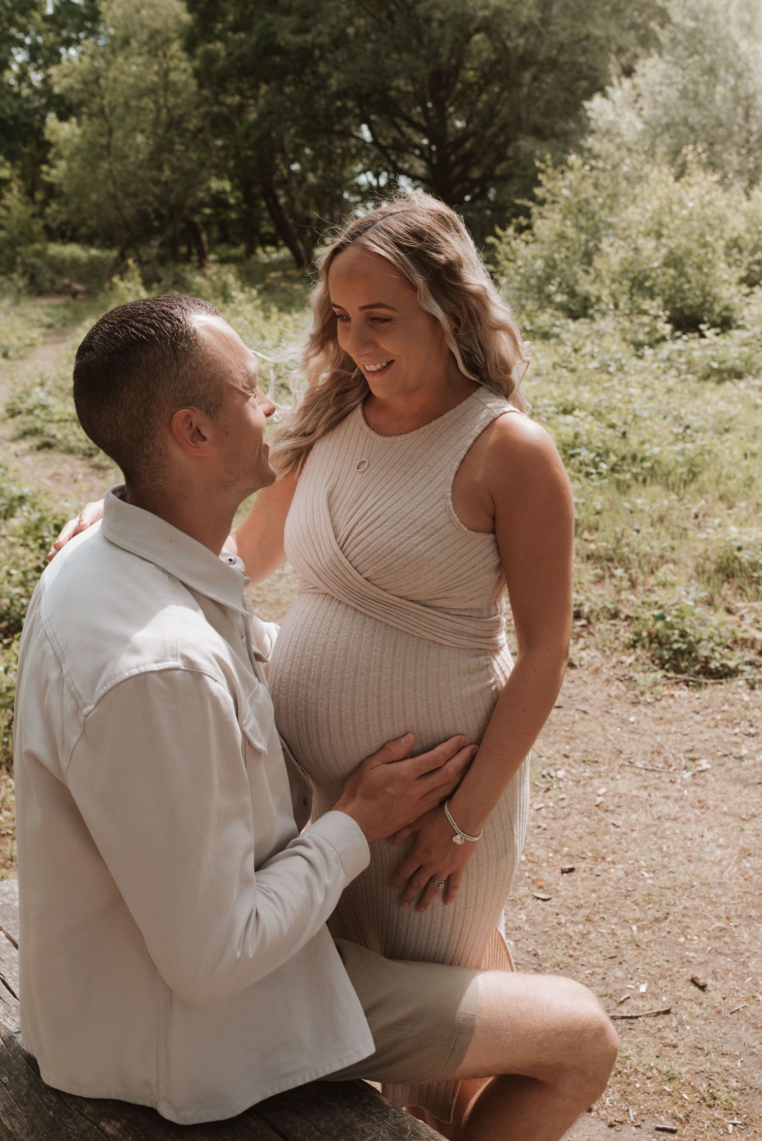 A romantic outdoor maternity photoshoot showing tender moments between a couple on a natural path.