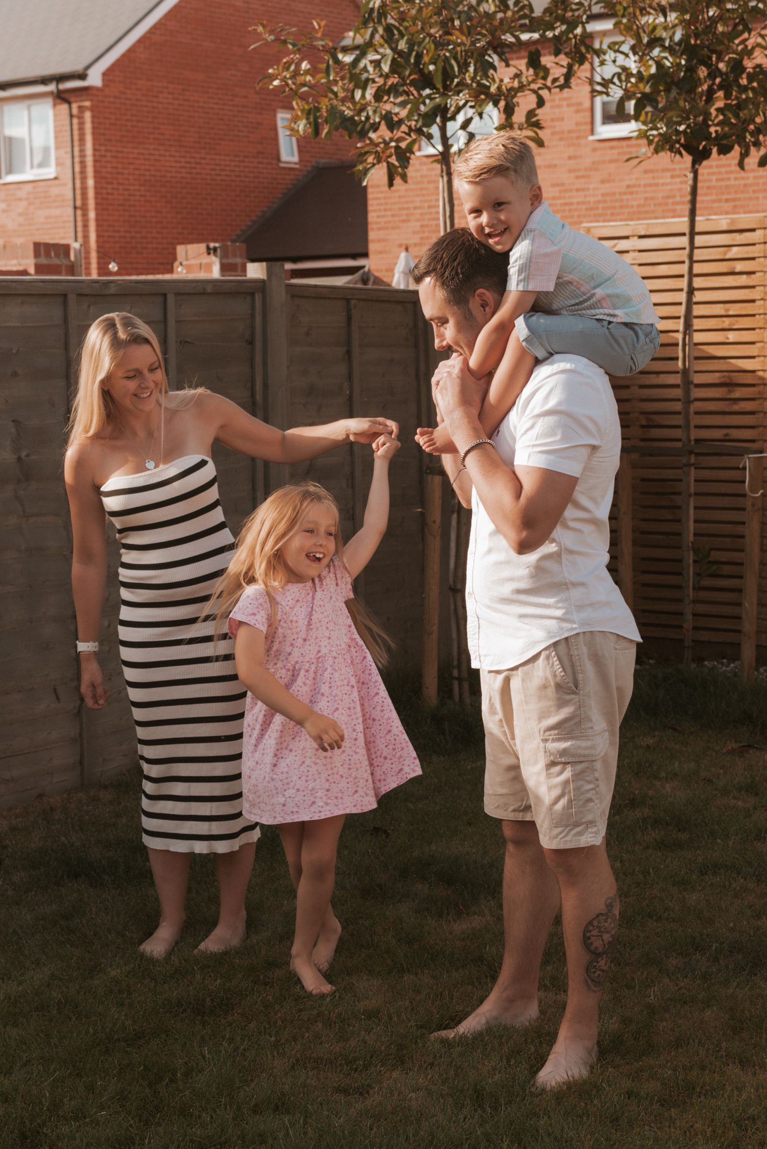 A family gathering in the backyard during a warm summer evening, dancing and playing together on the grass.