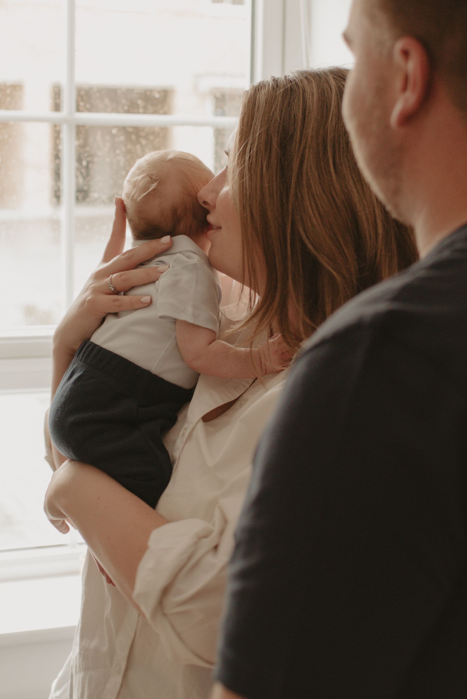 An intimate family moment by a window with soft natural light streaming in.