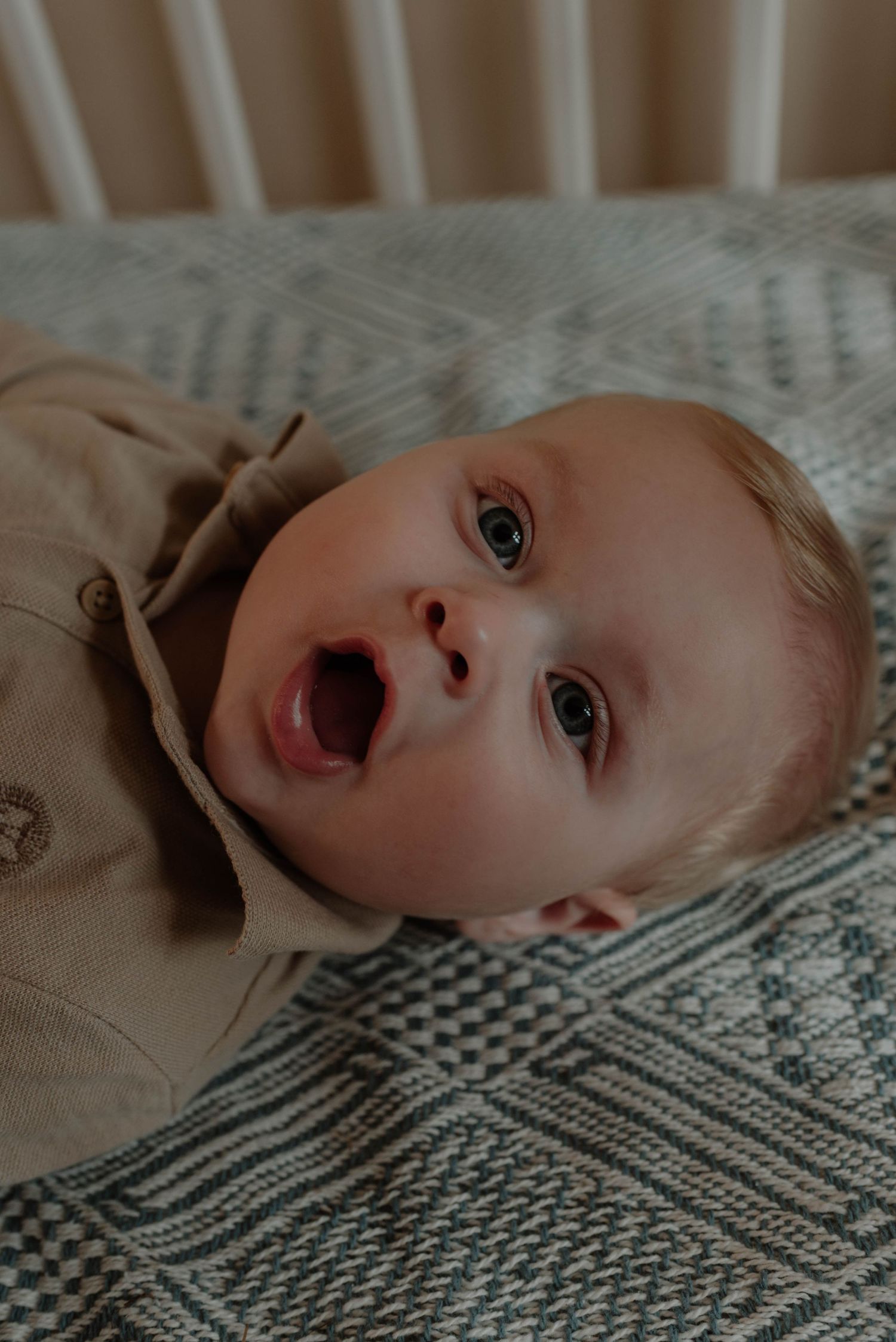 Close-up sequence of a baby lying on a patterned blanket with expressive eyes and changing facial expressions.