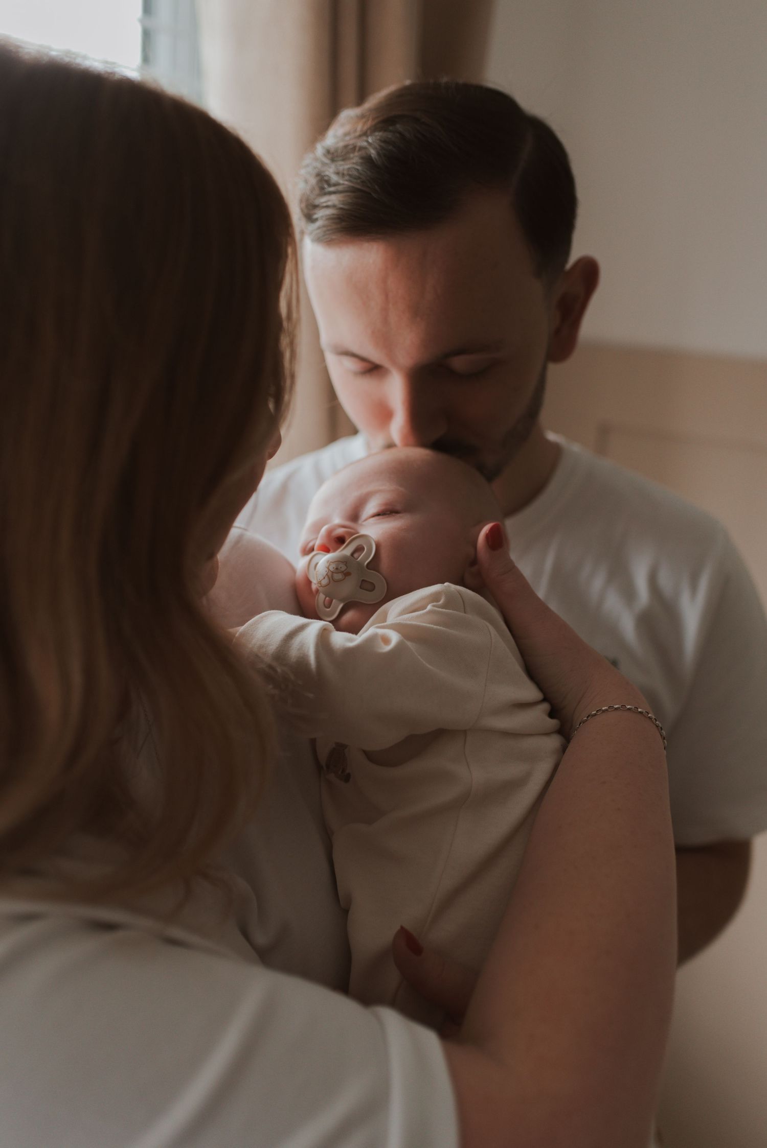 A tender family moment captured in soft lighting as a baby is held close.