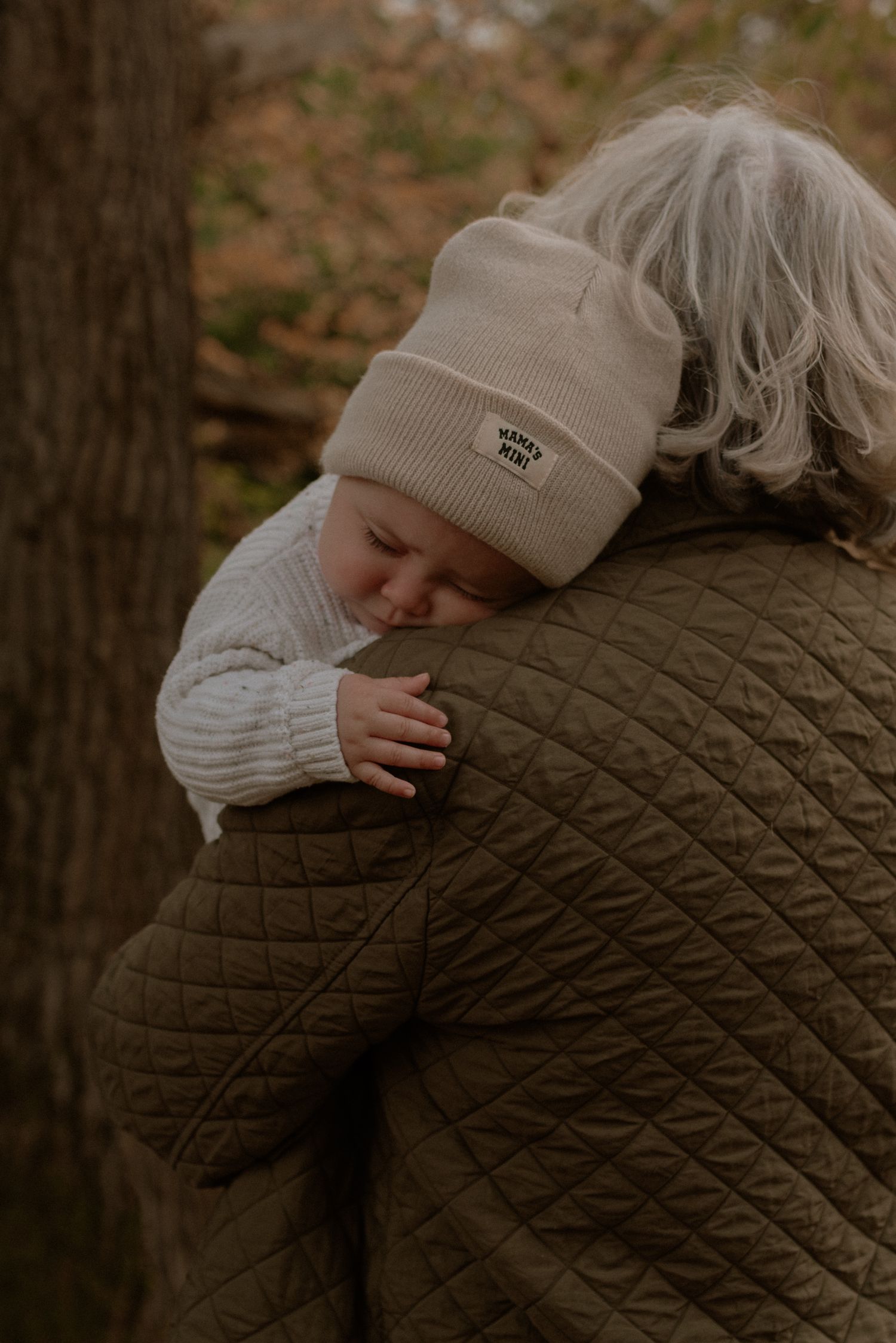 A tender embrace captured in a forest setting shows two people sharing an intimate hug against an autumn backdrop.
