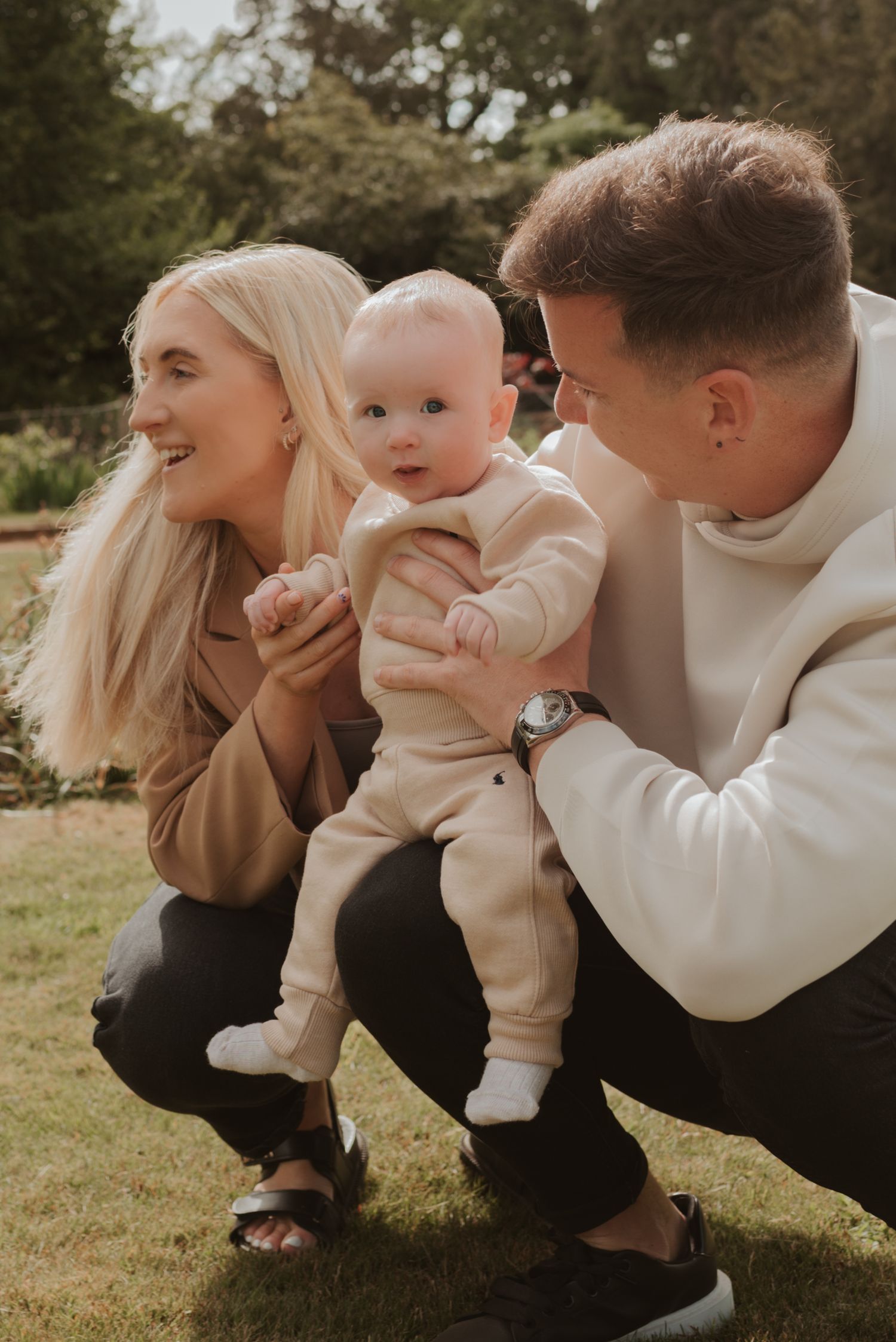 A family sharing a sweet moment together outdoors while crouching on grass.