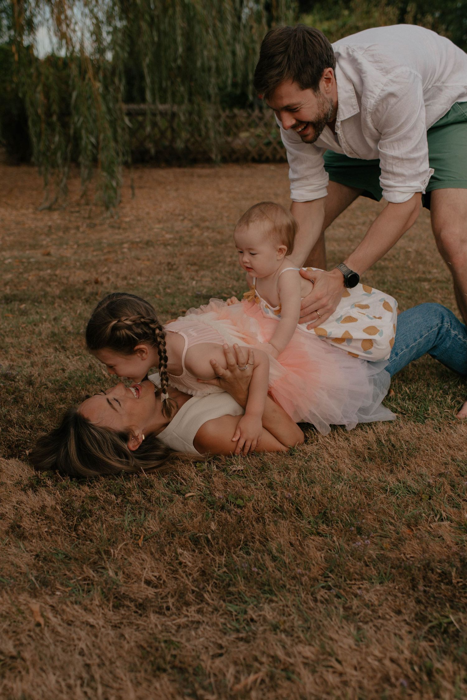 A playful family moment captured in a sequence of photos showing tickling and laughter on brown autumn grass.
