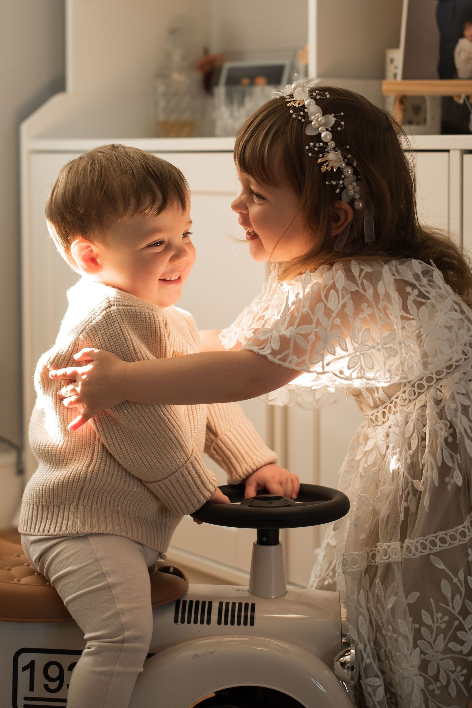 Two young children sharing a sweet moment while playing on a ride-on toy.