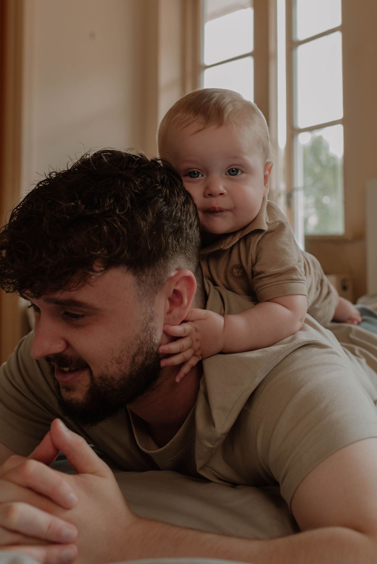 A tender moment between parent and child as they lay together on a bed in warm natural lighting.