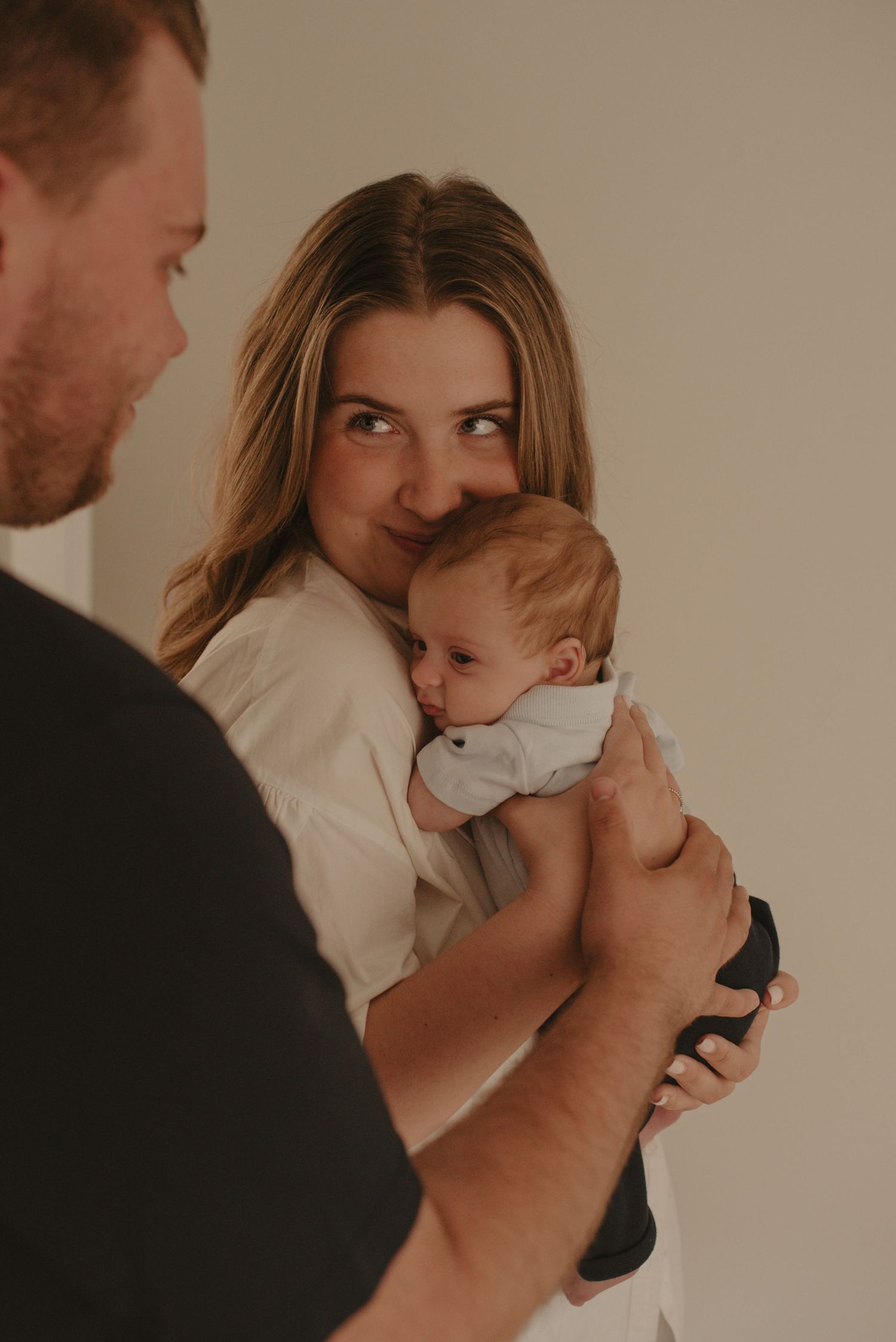 A tender family moment with a baby in white clothing being held close.