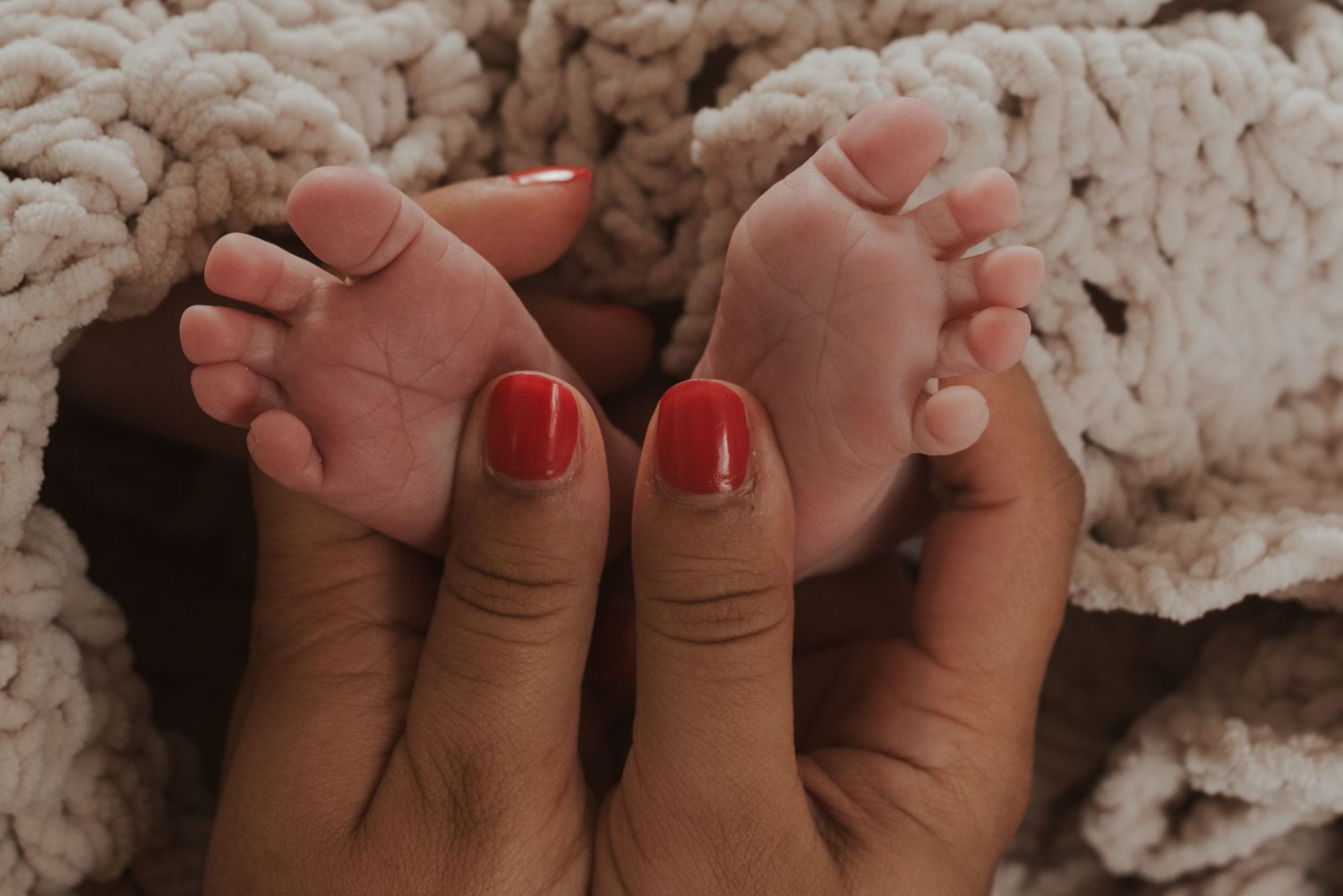 Close up of bare feet with red painted toenails against textured white background.