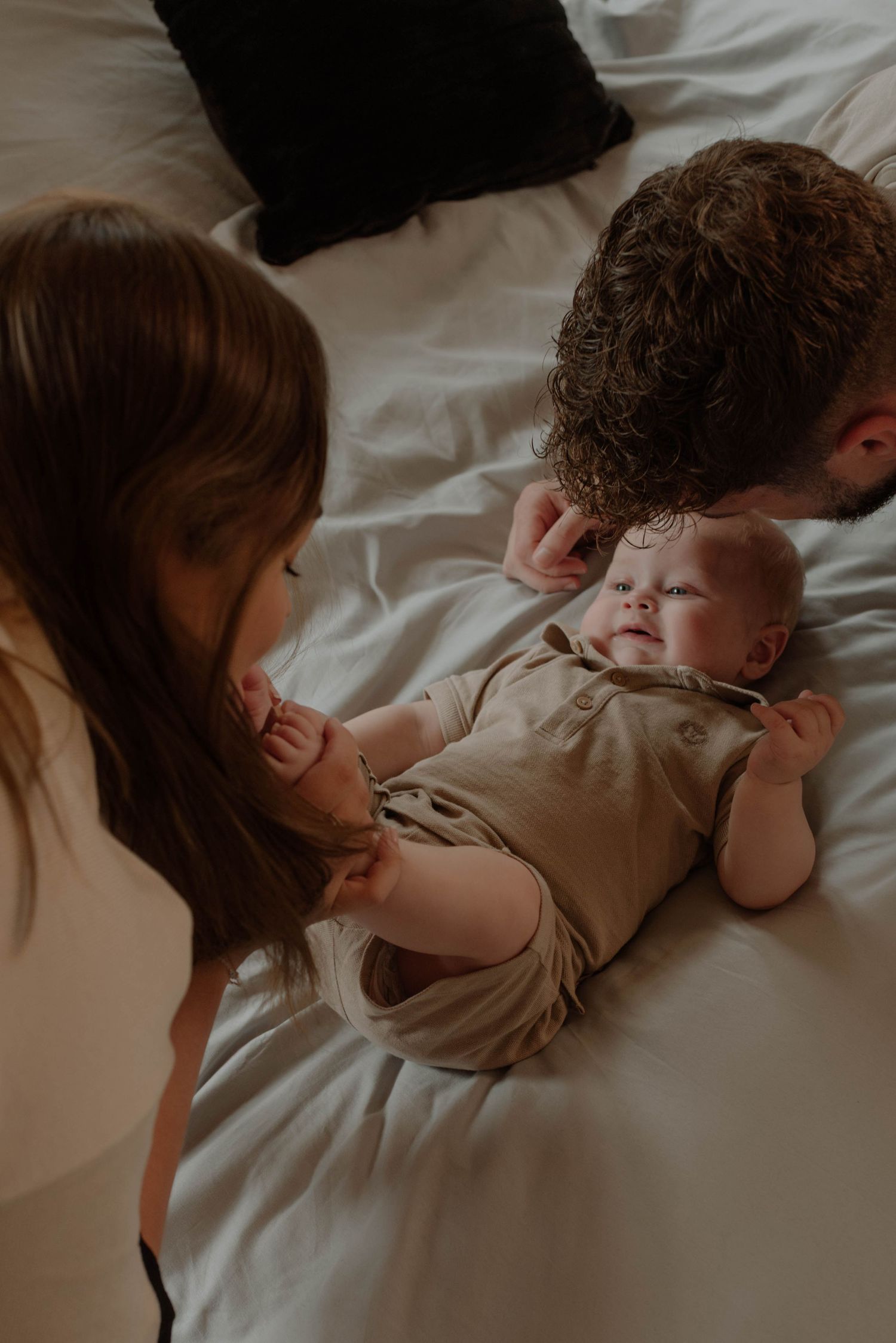 Two children lying close together on white bedding in a tender moment of connection and rest.