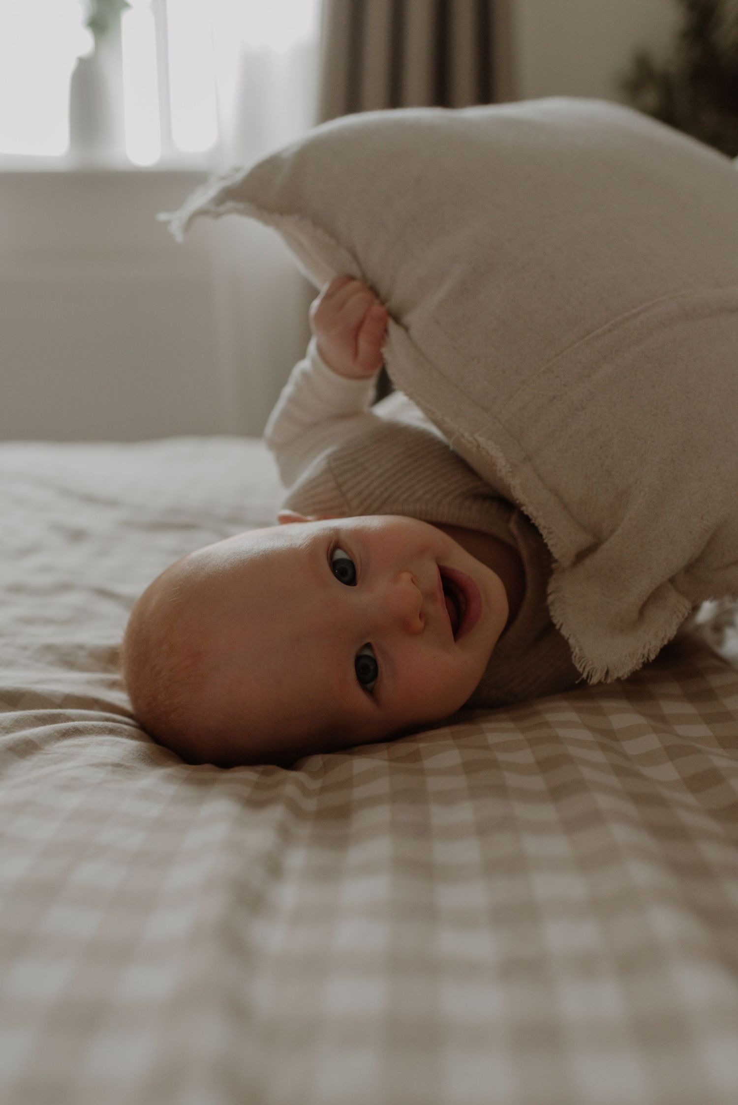 A small baby lies on white bedding while wrapped in a soft blanket, creating a peaceful and intimate moment.