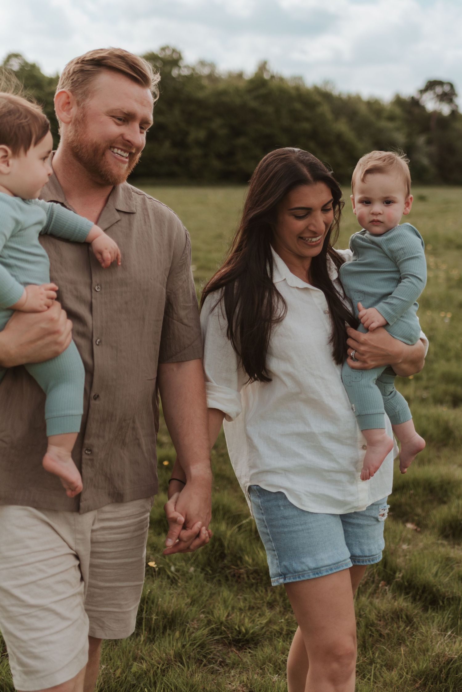 Family playing and laughing together in a grassy field on a sunny afternoon.