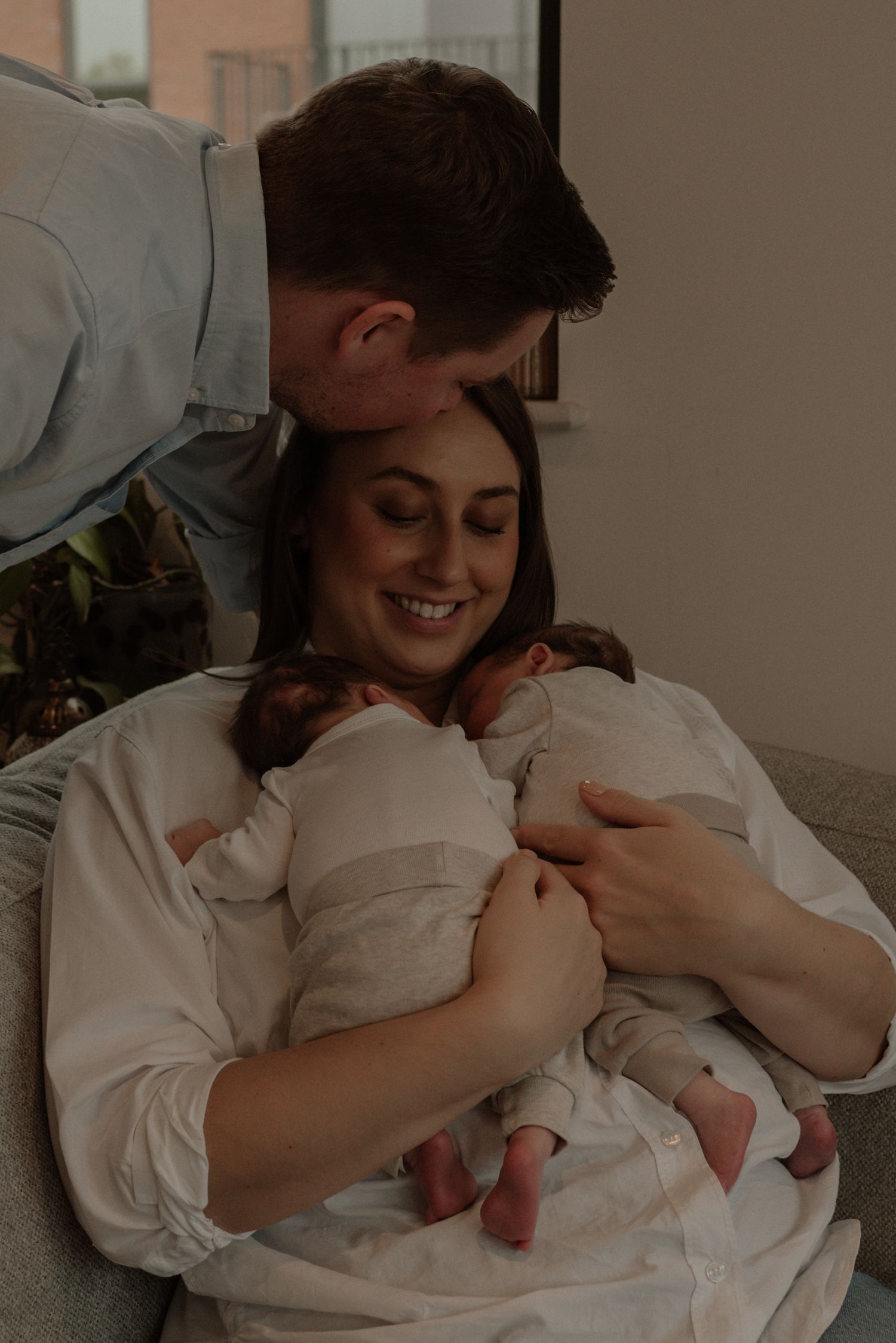A tender moment of a parent cradling and bonding with their newborn baby in white clothing.