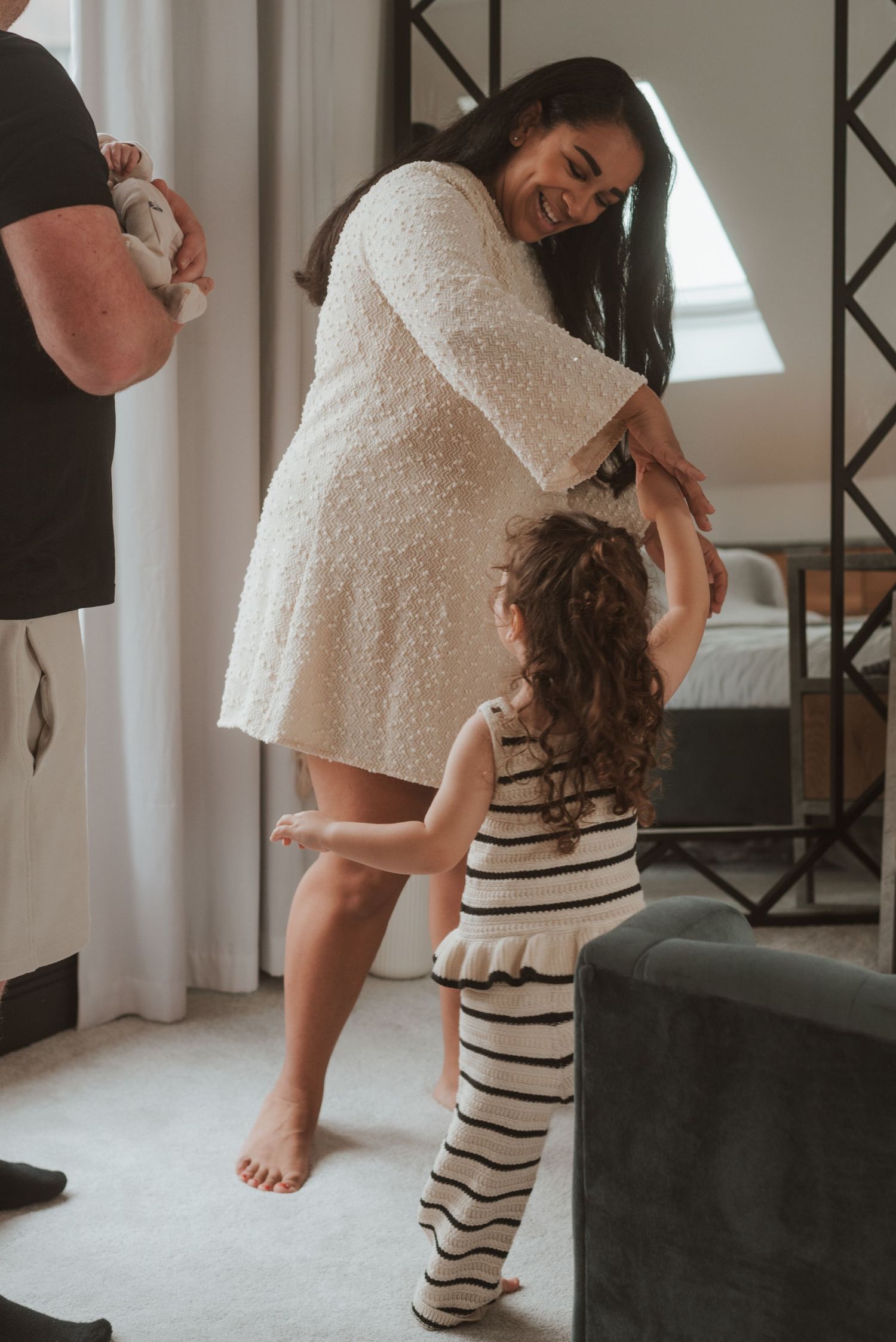 A sweet family moment with dancing and laughter in a sunlit room.
