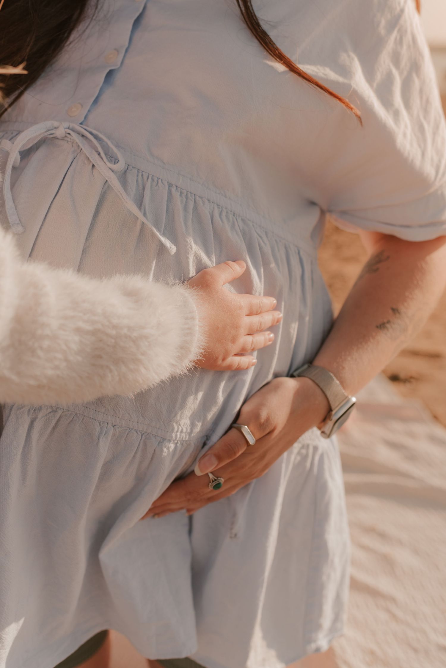 Close-up shots showing hands gently cradling a baby bump in soft lighting.