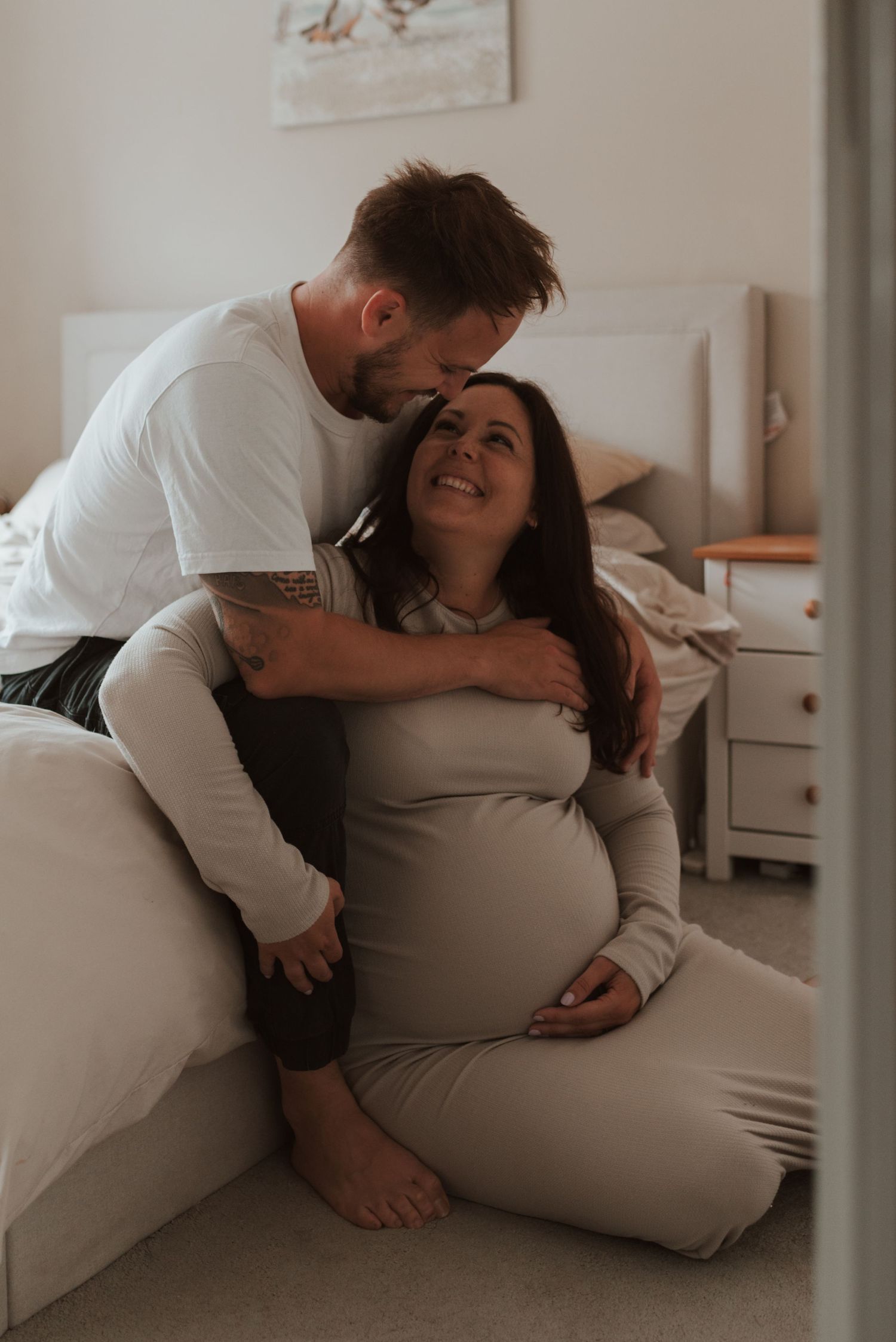 Intimate maternity moment captured in soft indoor lighting.