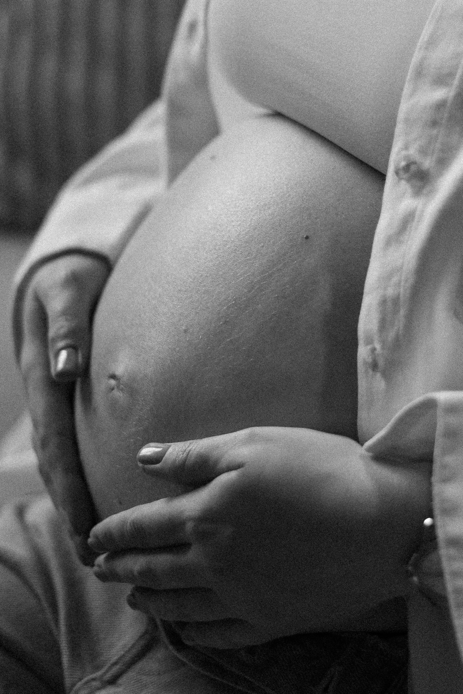 A series of black and white closeup photos showing a pregnant belly in different artistic angles.