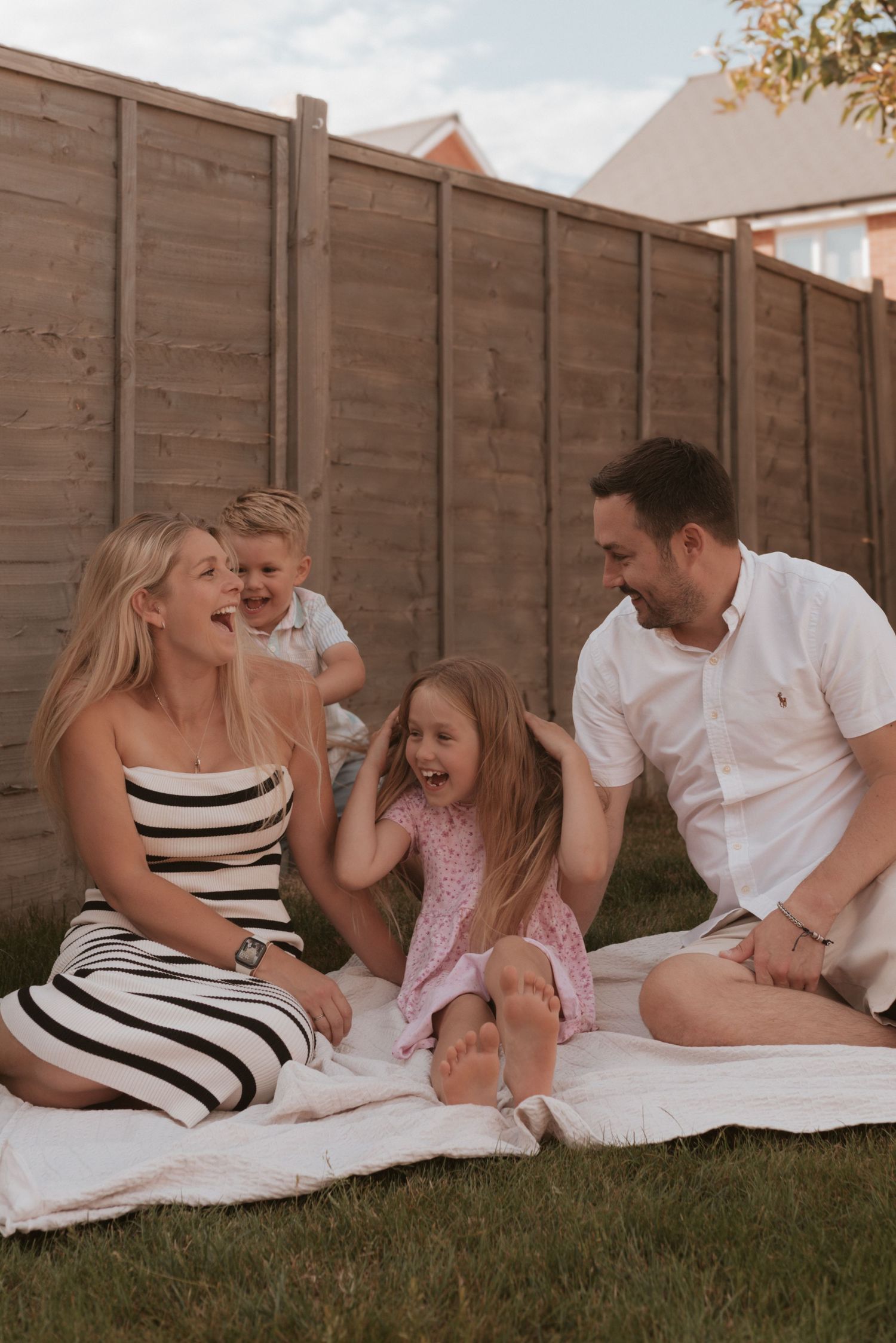 A family enjoying quality time together while sitting on a blanket in their backyard on a summer evening.