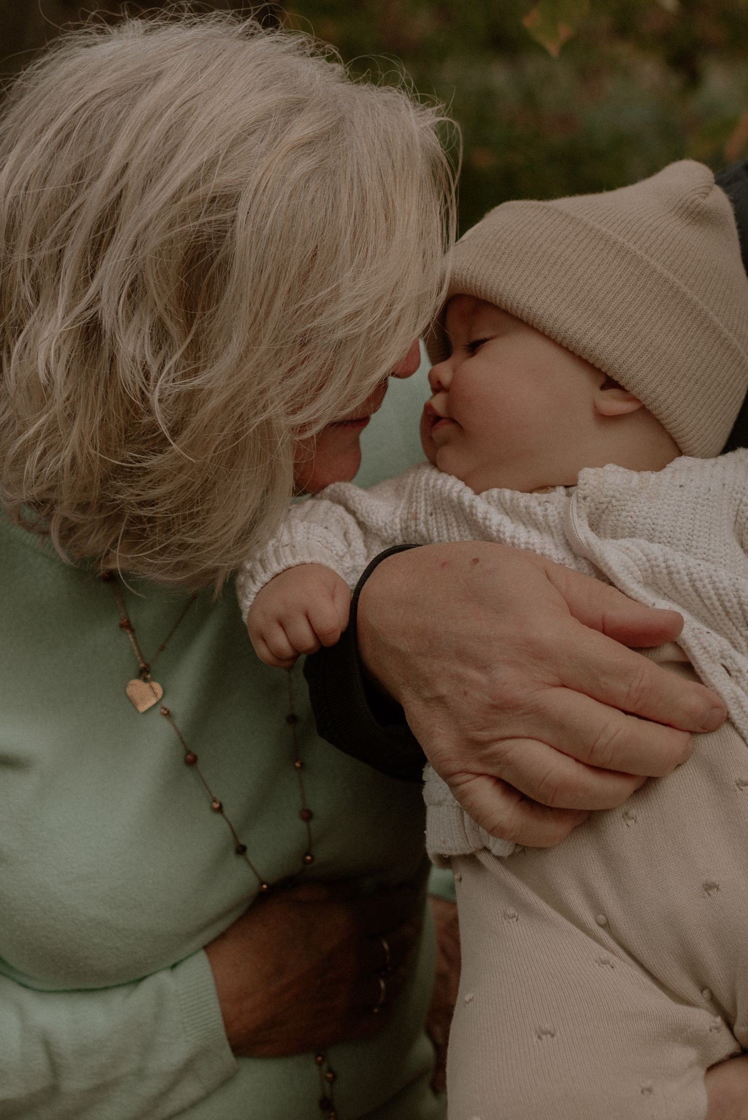 Tender close-up photo showing a gentle kiss and embrace in muted, moody lighting.